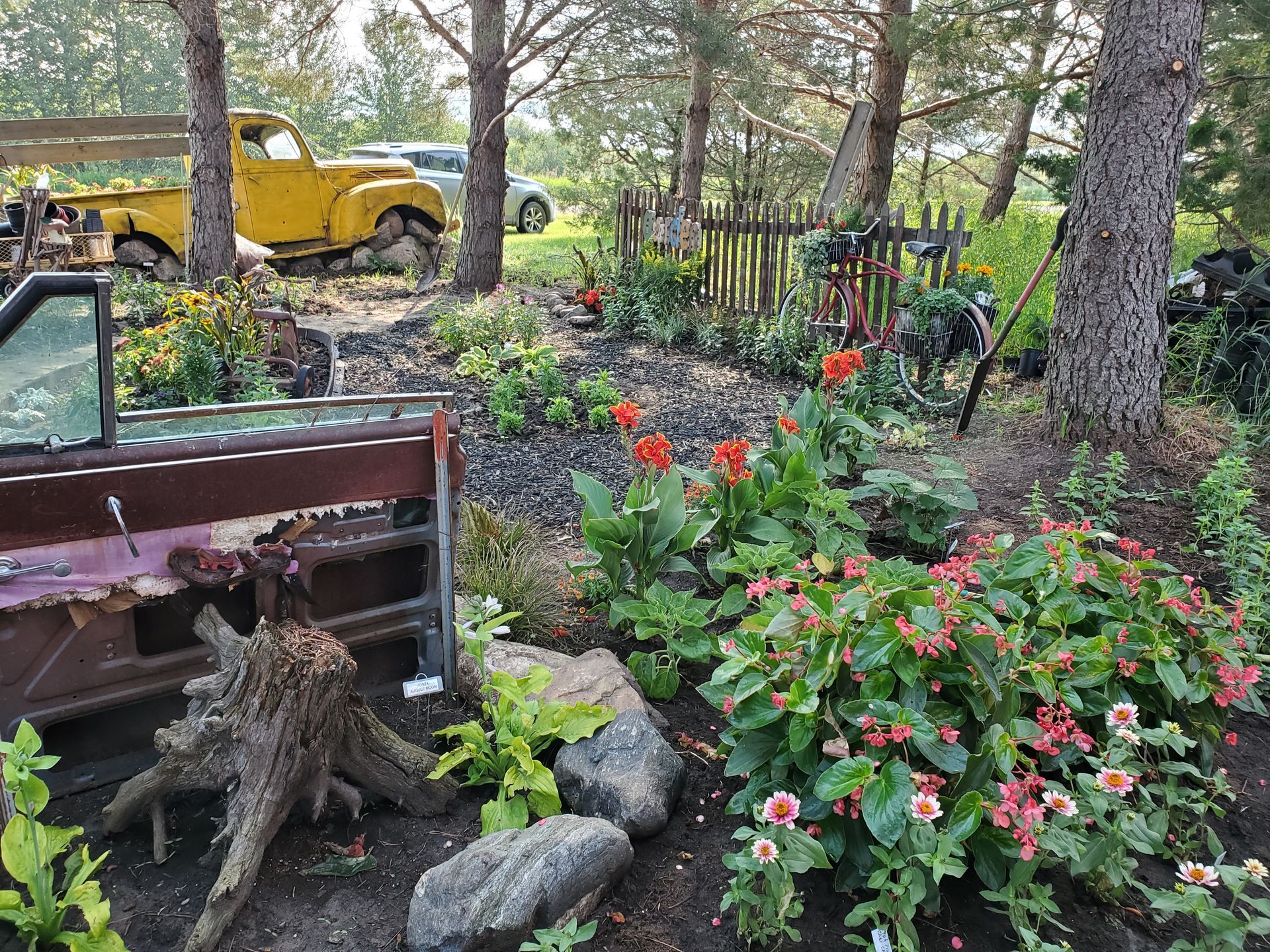 Woman arranging flowers in a purple watering can, smiling. Light-filled room with supplies on a table.