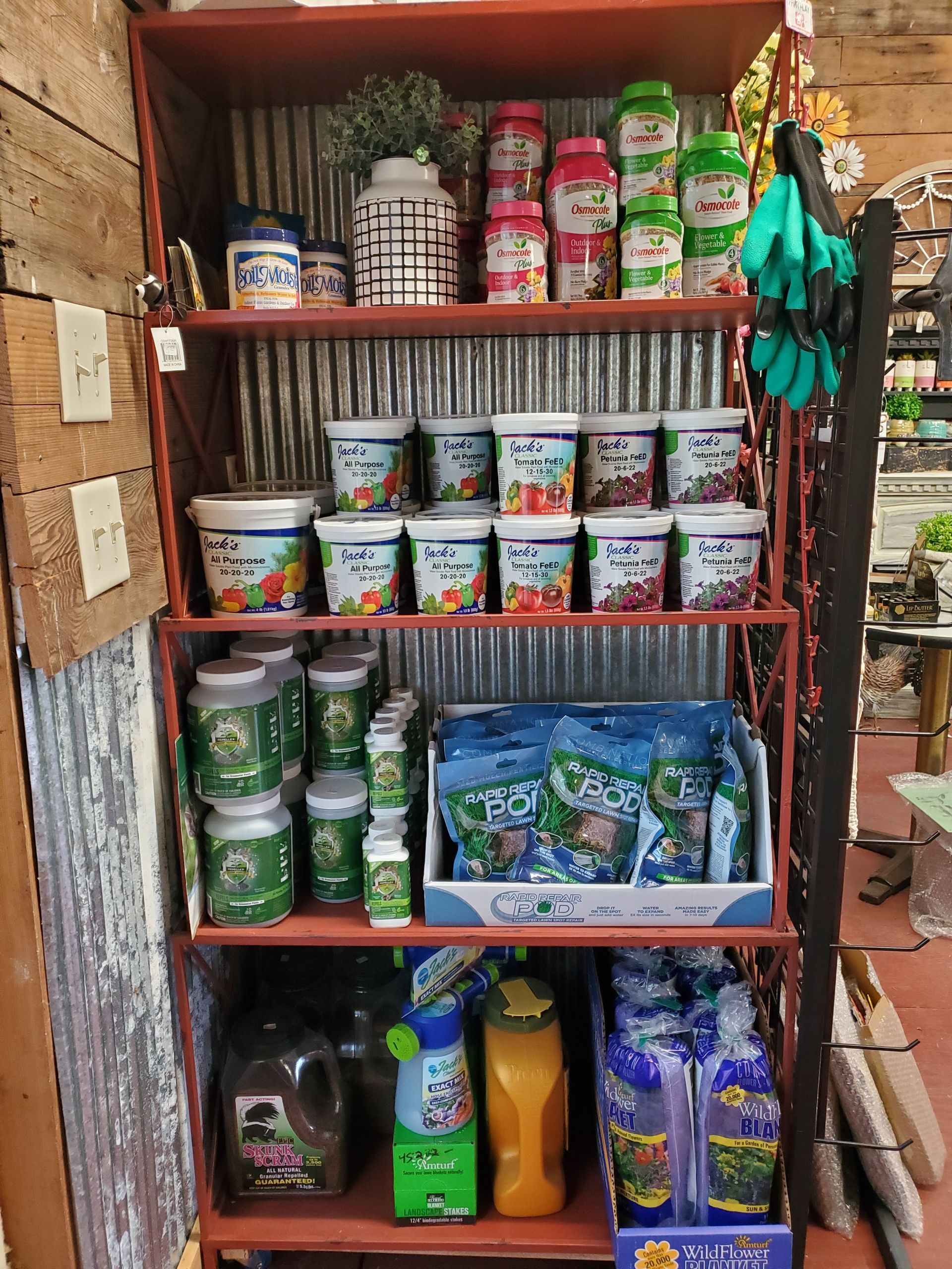 Shelving unit stocked with various gardening supplies, including containers of fertilizer and plant food.