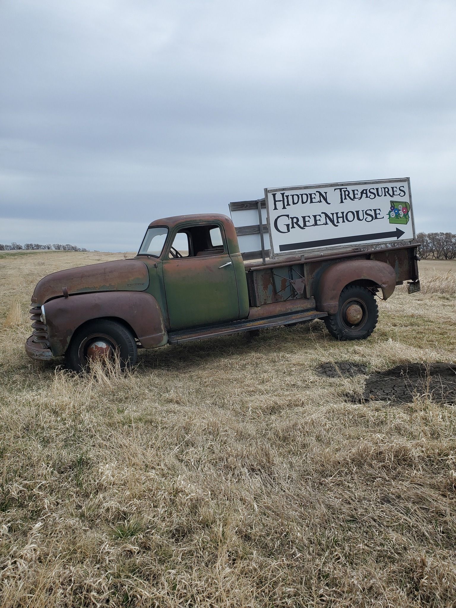 Rusty vintage truck in a field, with a sign that reads 