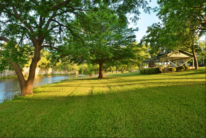 A park with trees and a gazebo in the background