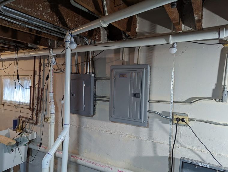 A technician wearing safety glasses works on solar inverter equipment mounted on a brick wall.