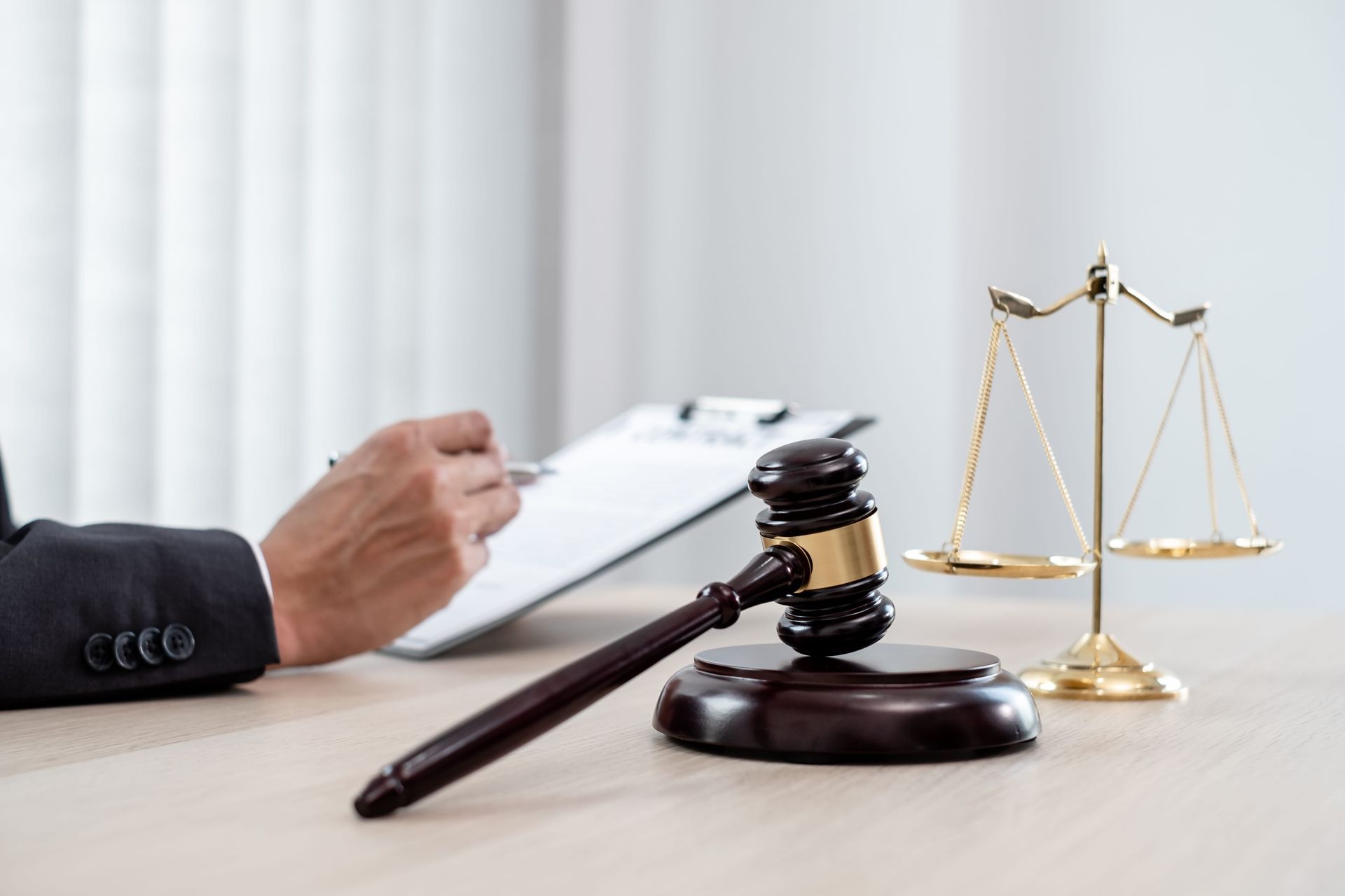 Lawyer’s desk with gavel, scales of justice, and hand writing on a clipboard