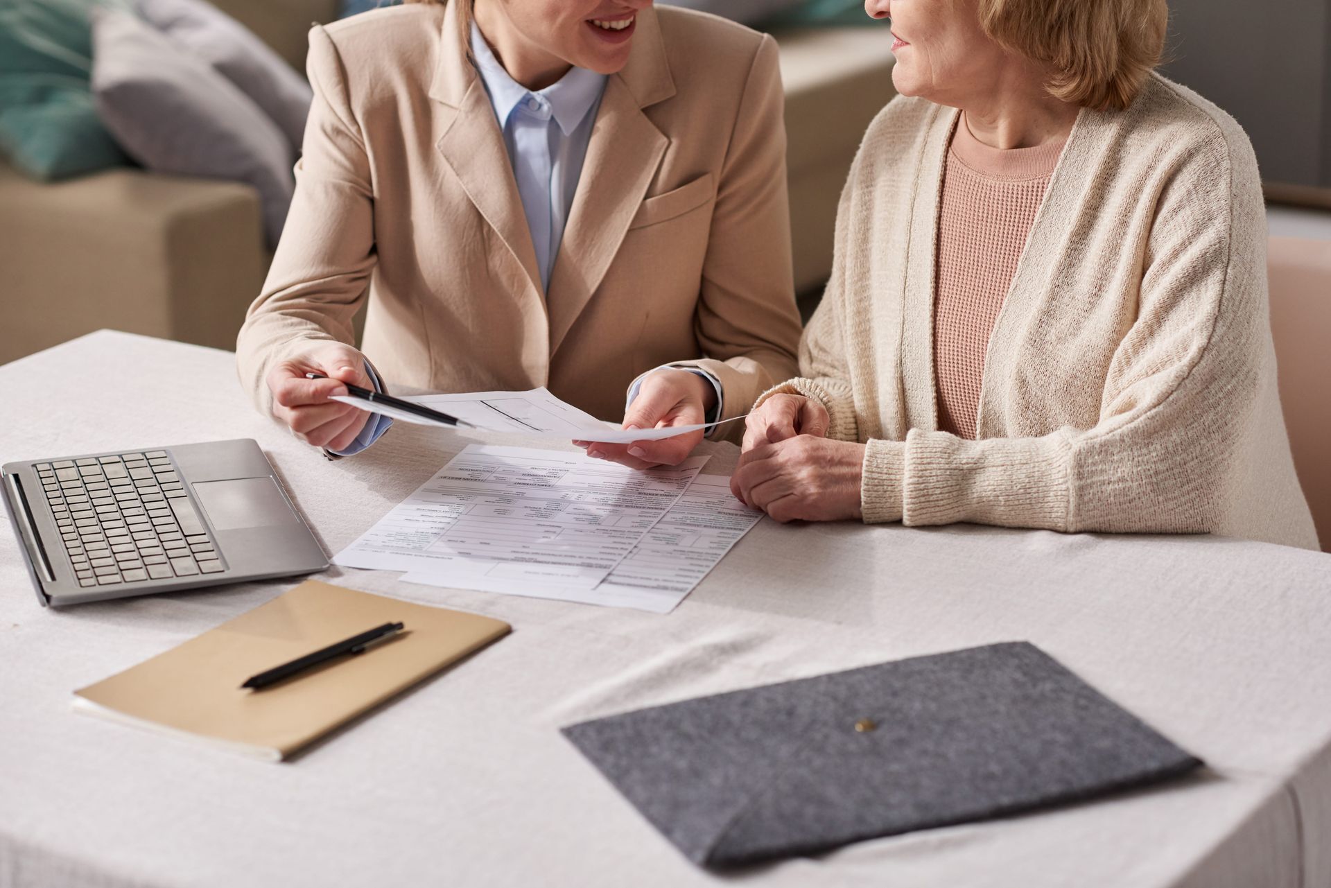 Two people reviewing financial documents at a table with a calculator and folders