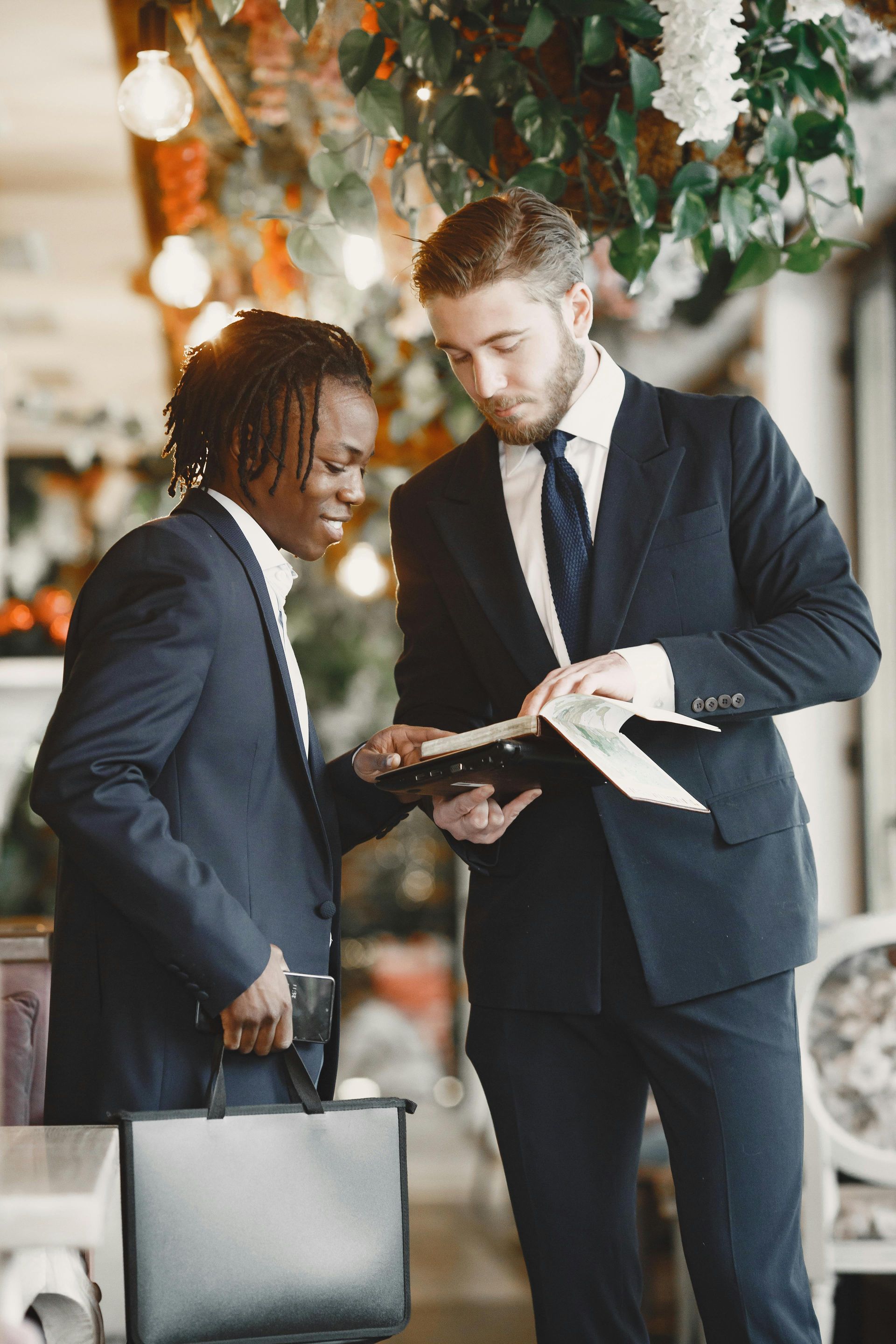 Two people in formal business suits standing in a restaurant, reviewing documents together.
