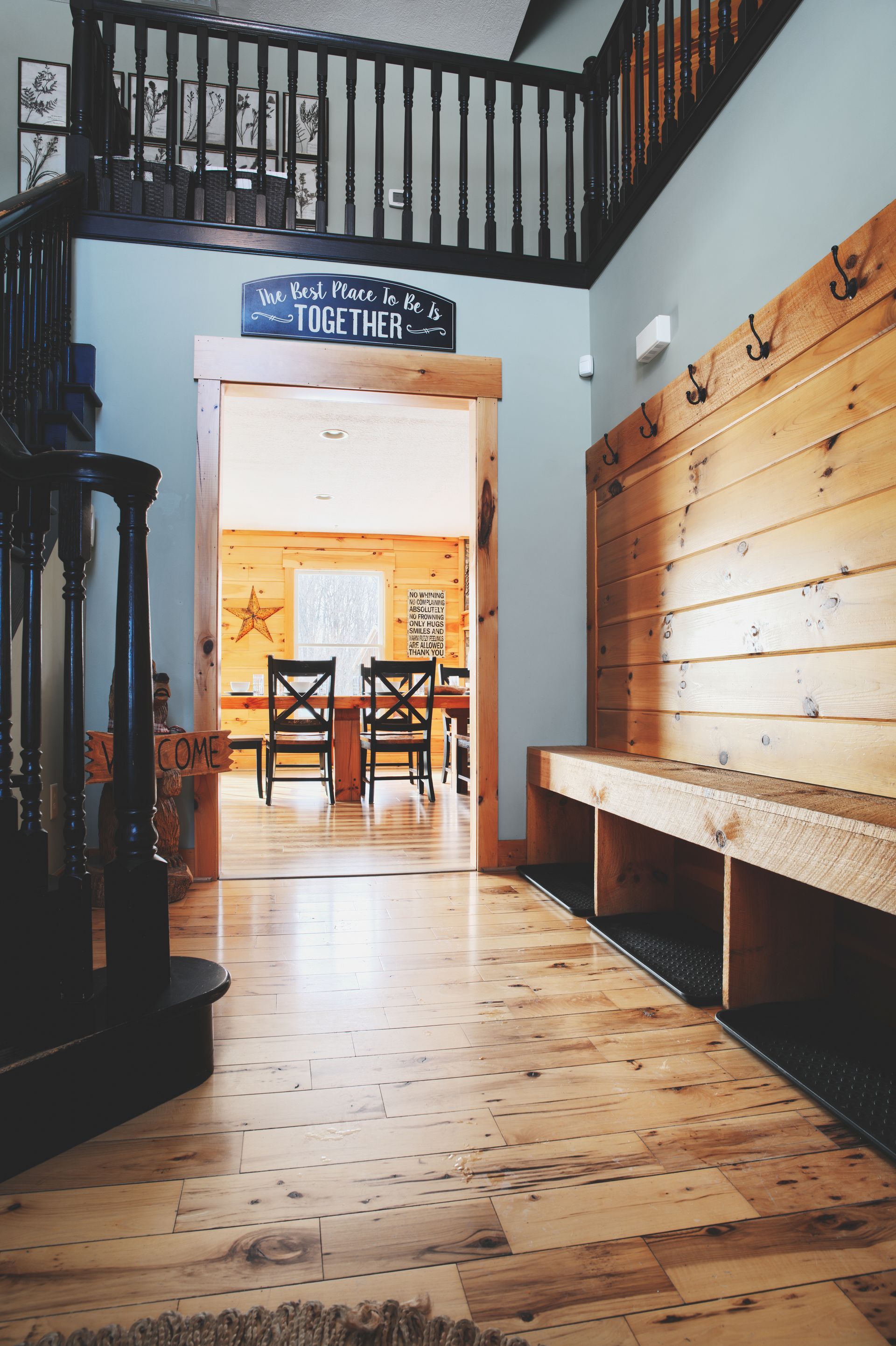 A hallway with a wooden bench and stairs leading to a dining room