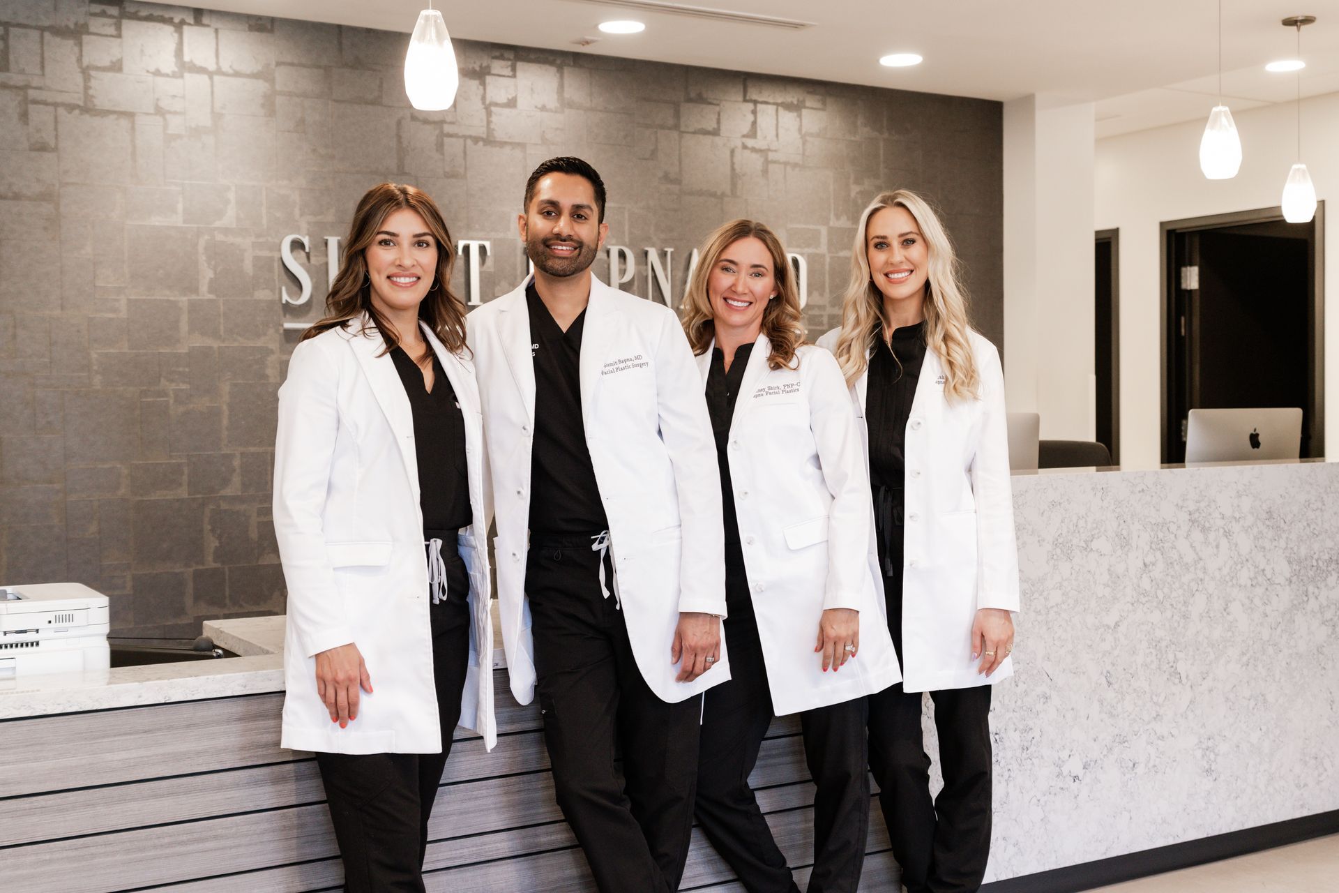 A group of doctors are posing for a picture in front of a reception desk.