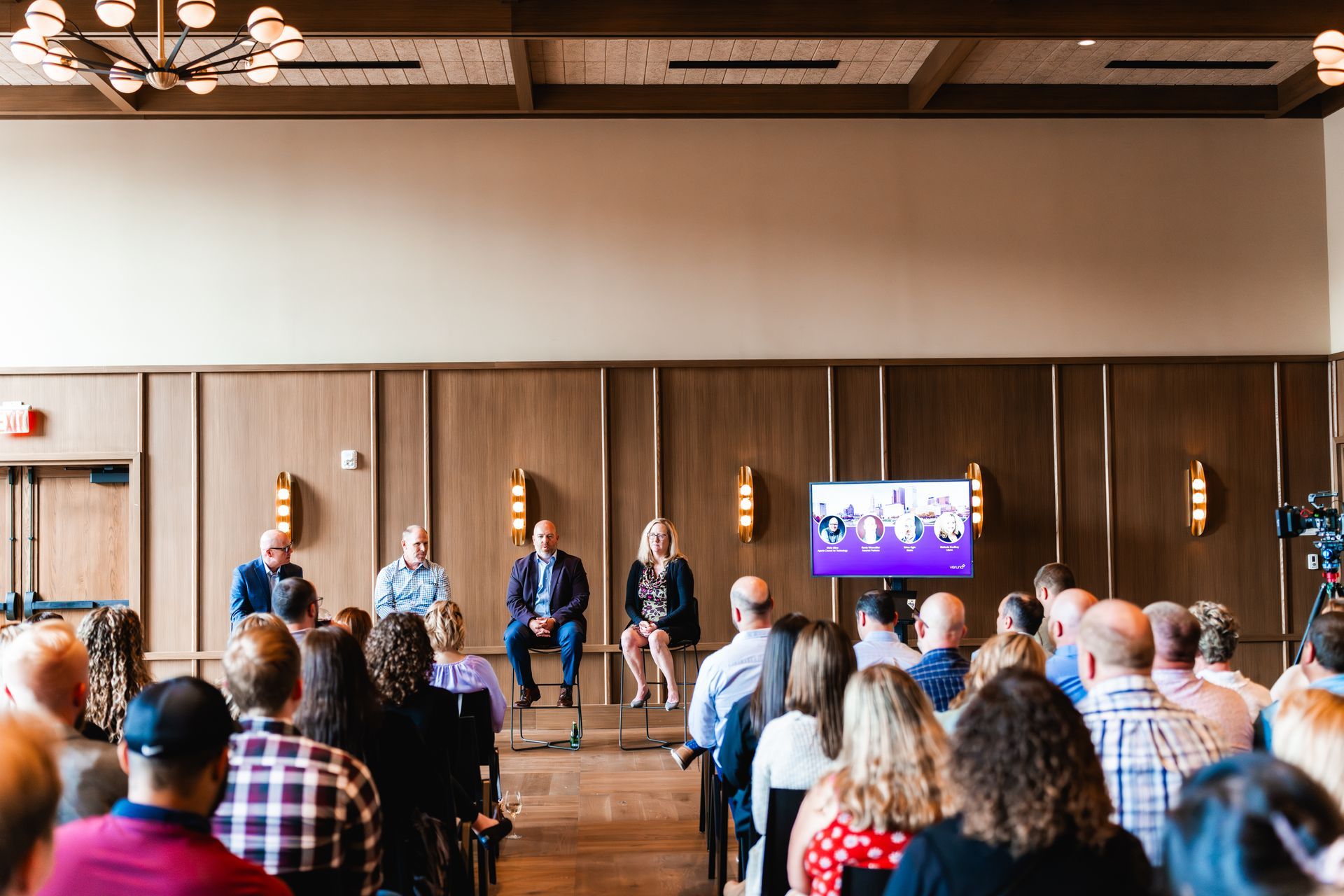 A large group of people are sitting in a room watching a panel.