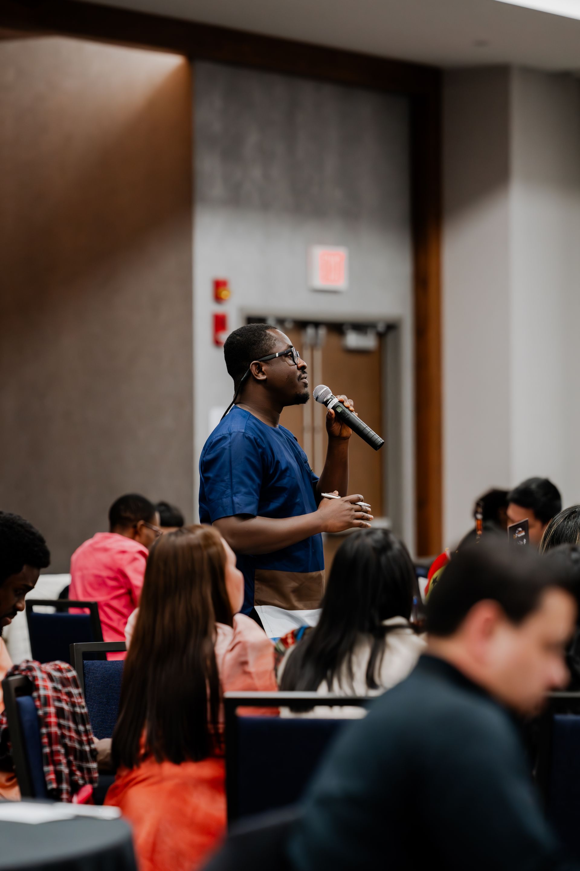 A man is speaking into a microphone in front of a group of people.