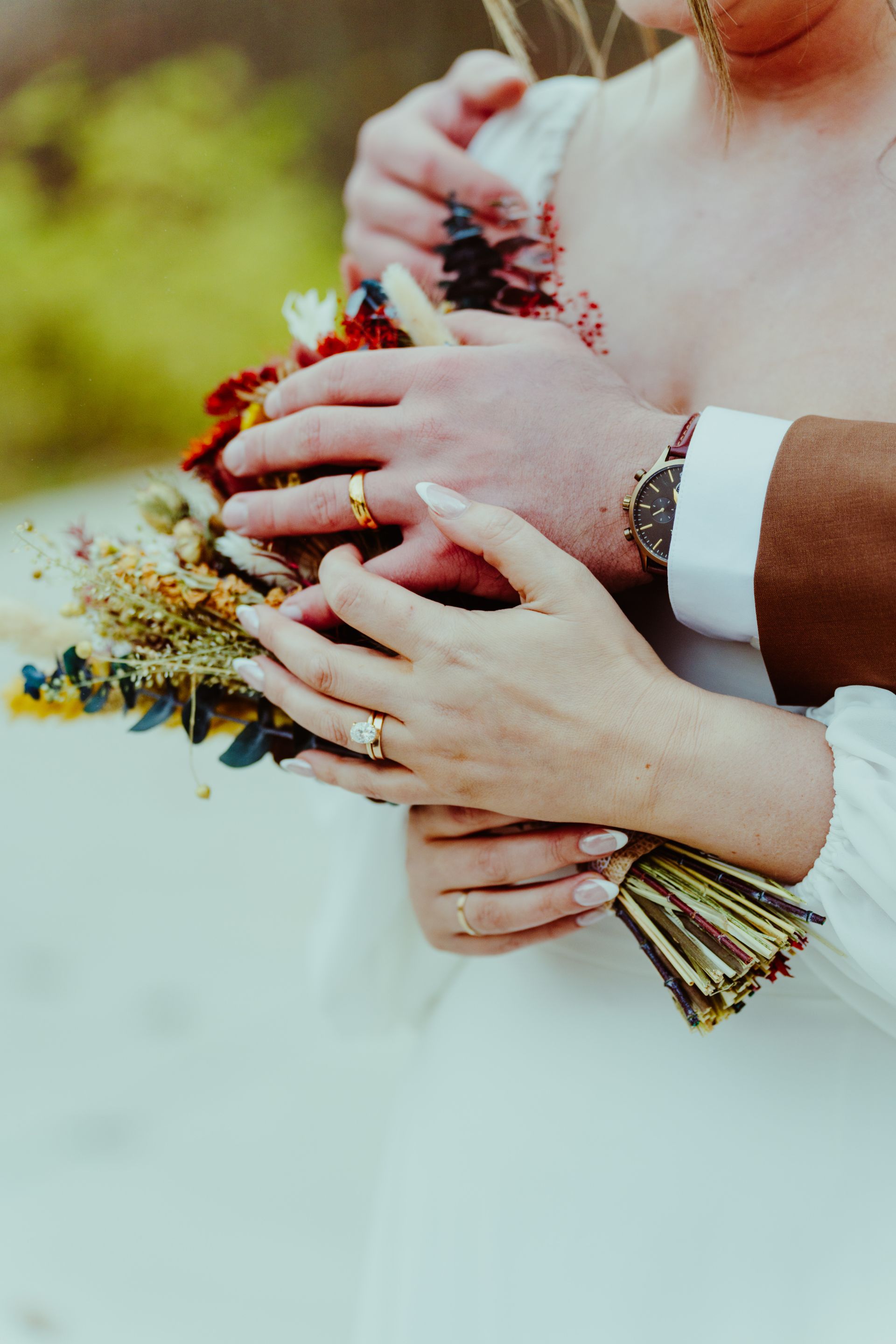 a close up of a bride and groom holding a bouquet of flowers .