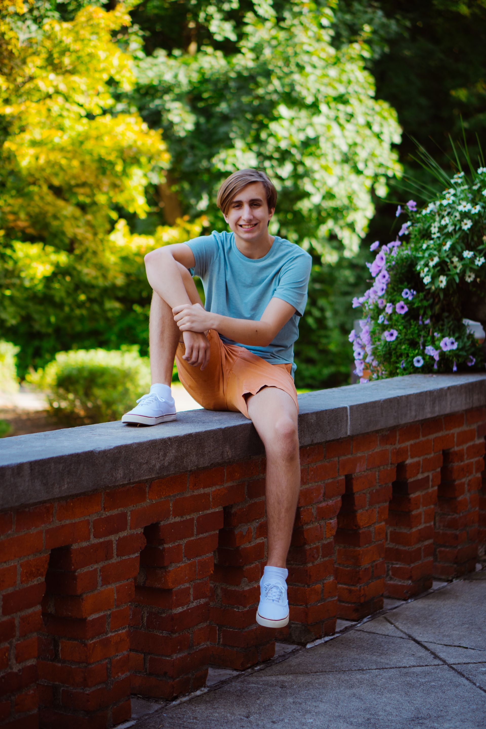 a young man is sitting on a brick wall .