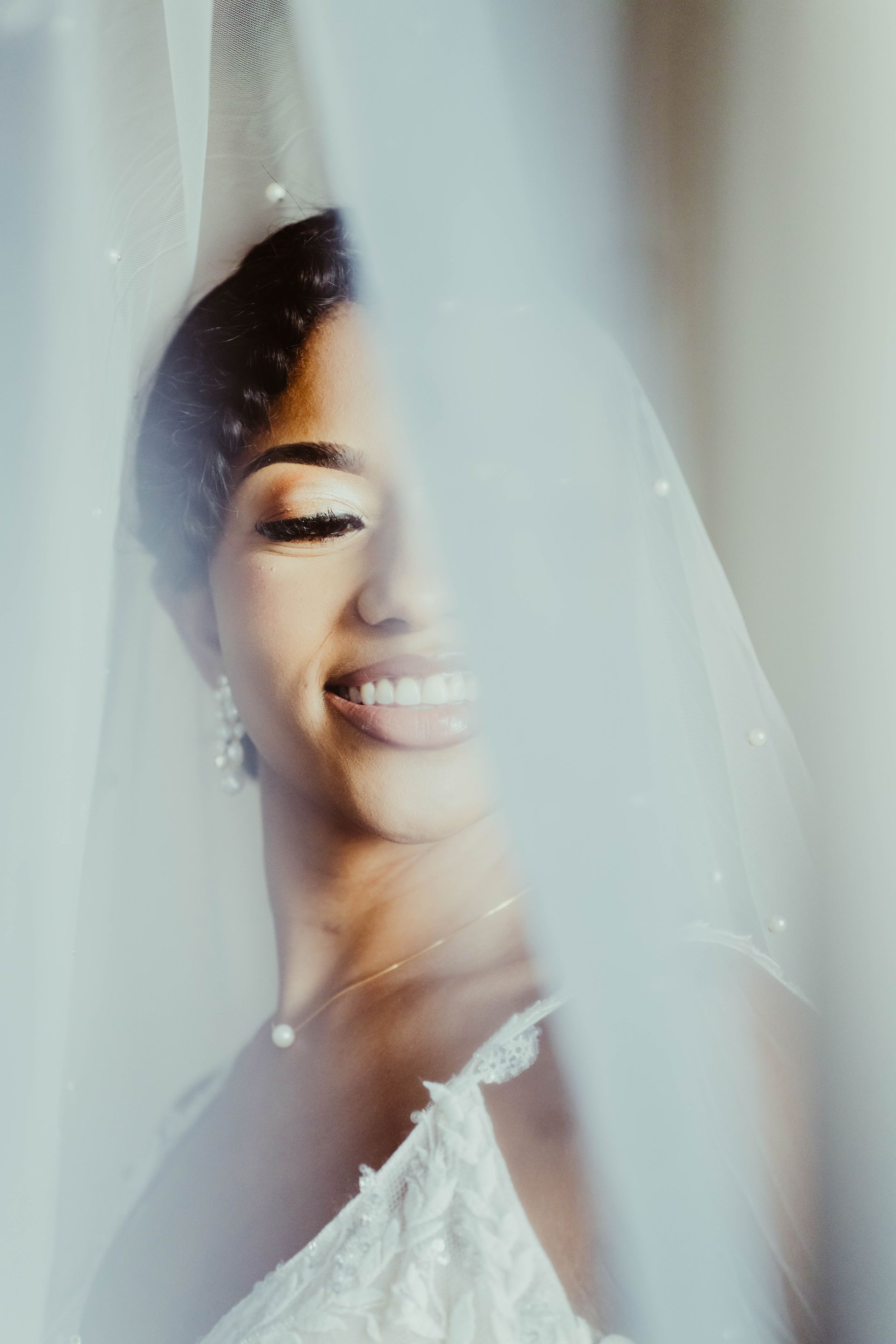 a close up of a bride wearing a veil and smiling .