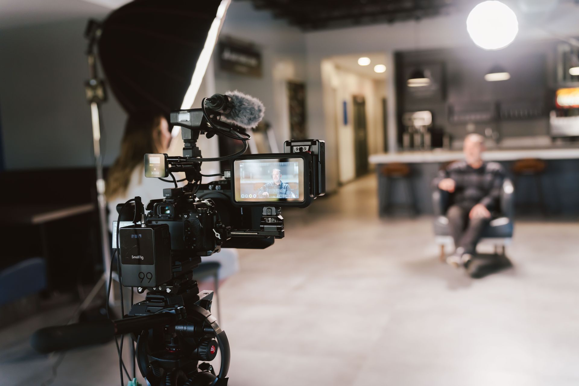 a woman is recording a man sitting in a chair with a camera .