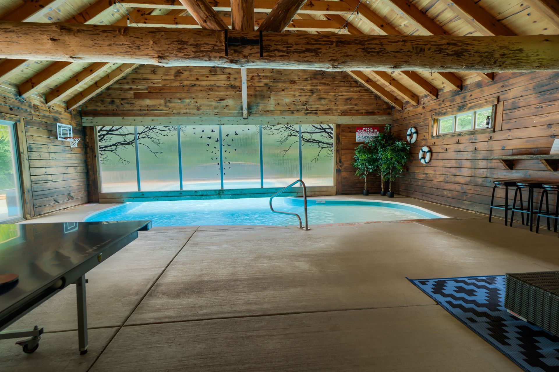 a large indoor swimming pool in a log cabin with a ping pong table .