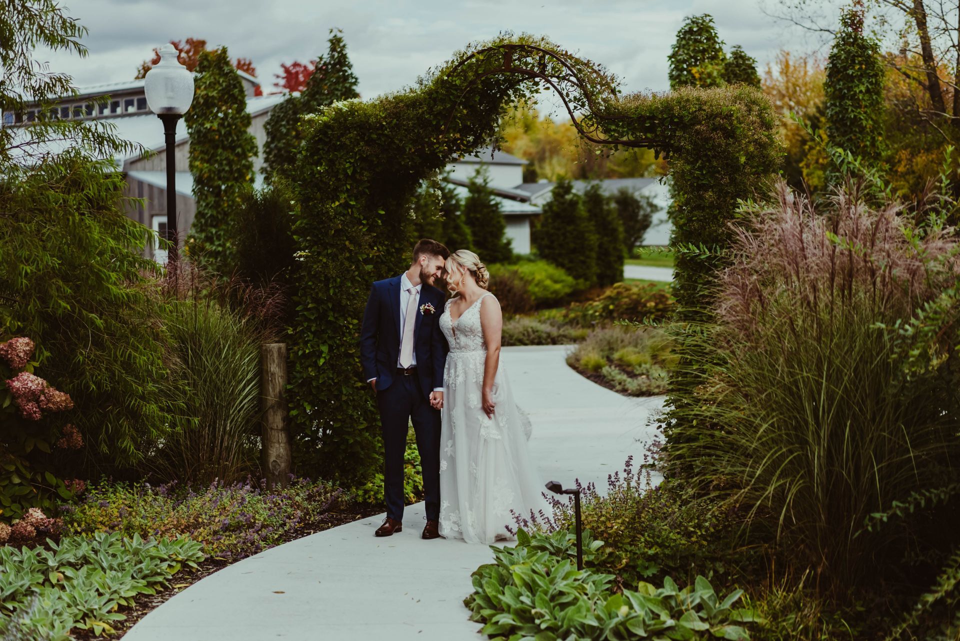 a bride and groom are walking down a path in a garden .