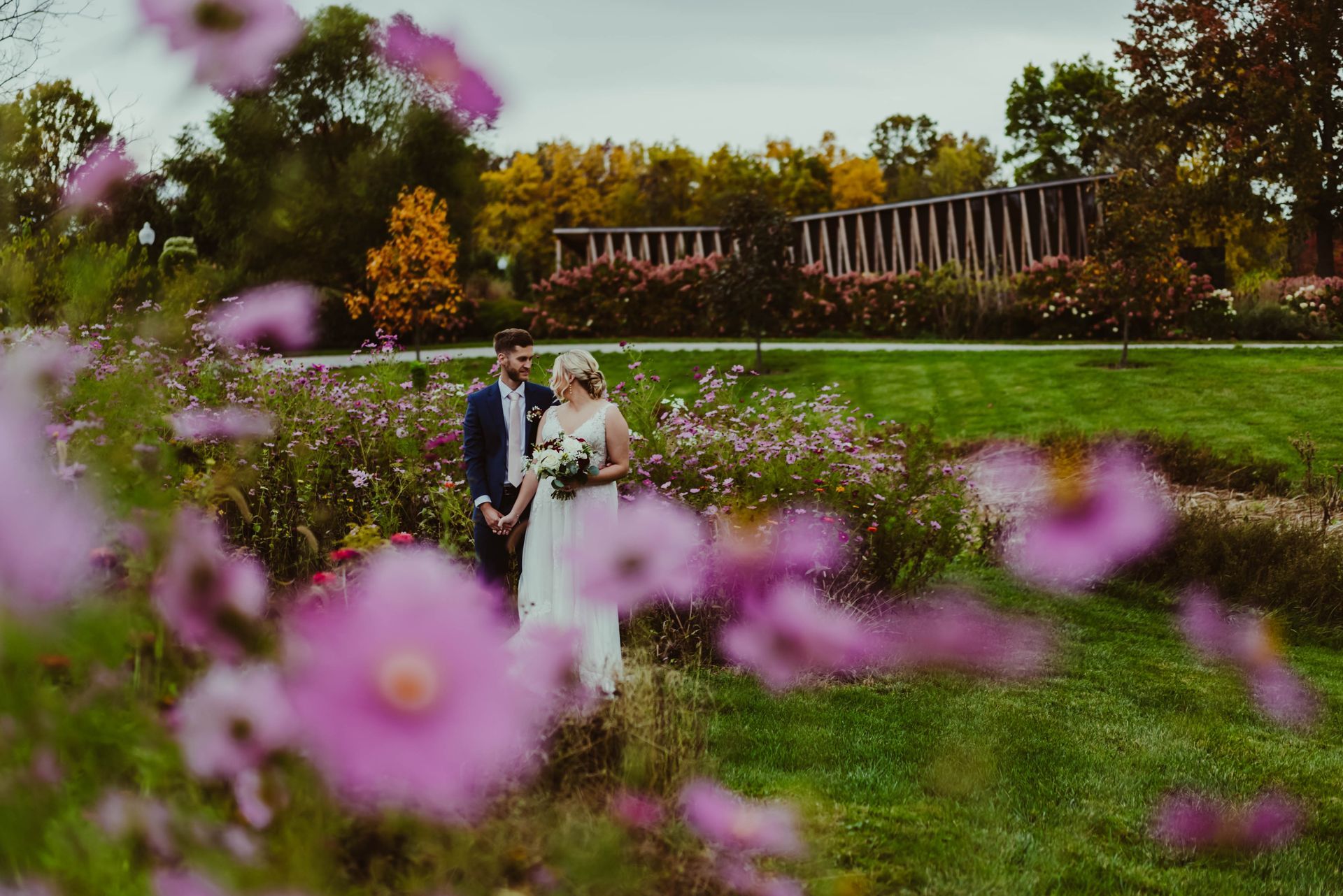 a bride and groom are standing in a field of purple flowers .
