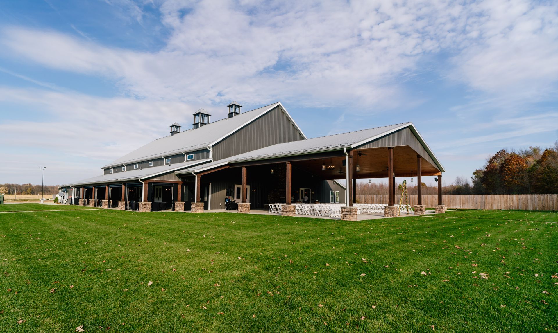 a large barn with a covered porch is sitting on top of a lush green field .