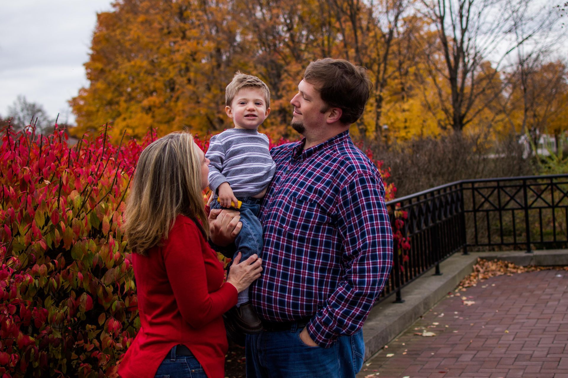 a man and woman are holding a baby in a park .