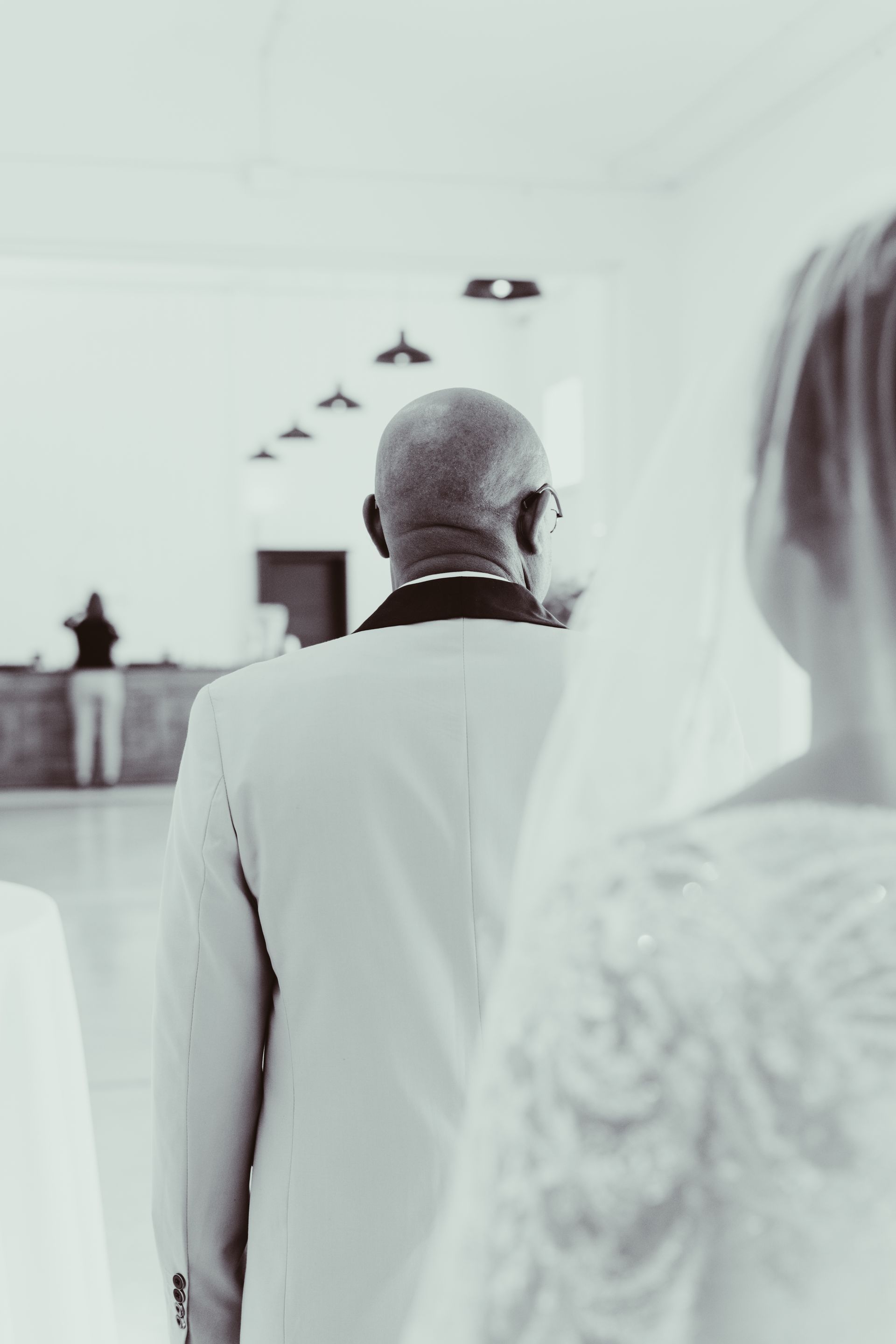 People standing at the front of a bright church ceremony, viewed from behind