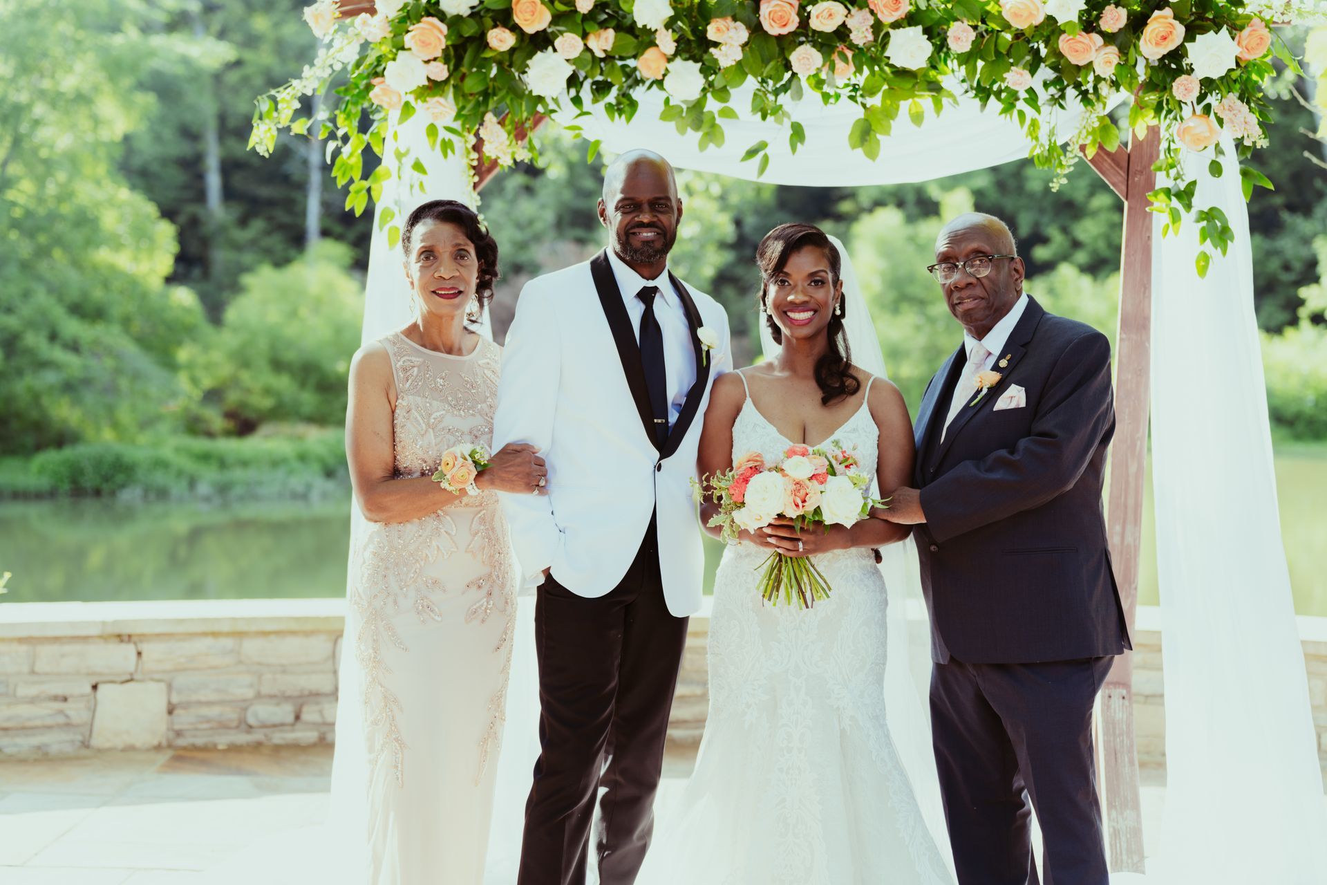 A bride and groom are posing for a picture with their parents at their wedding.