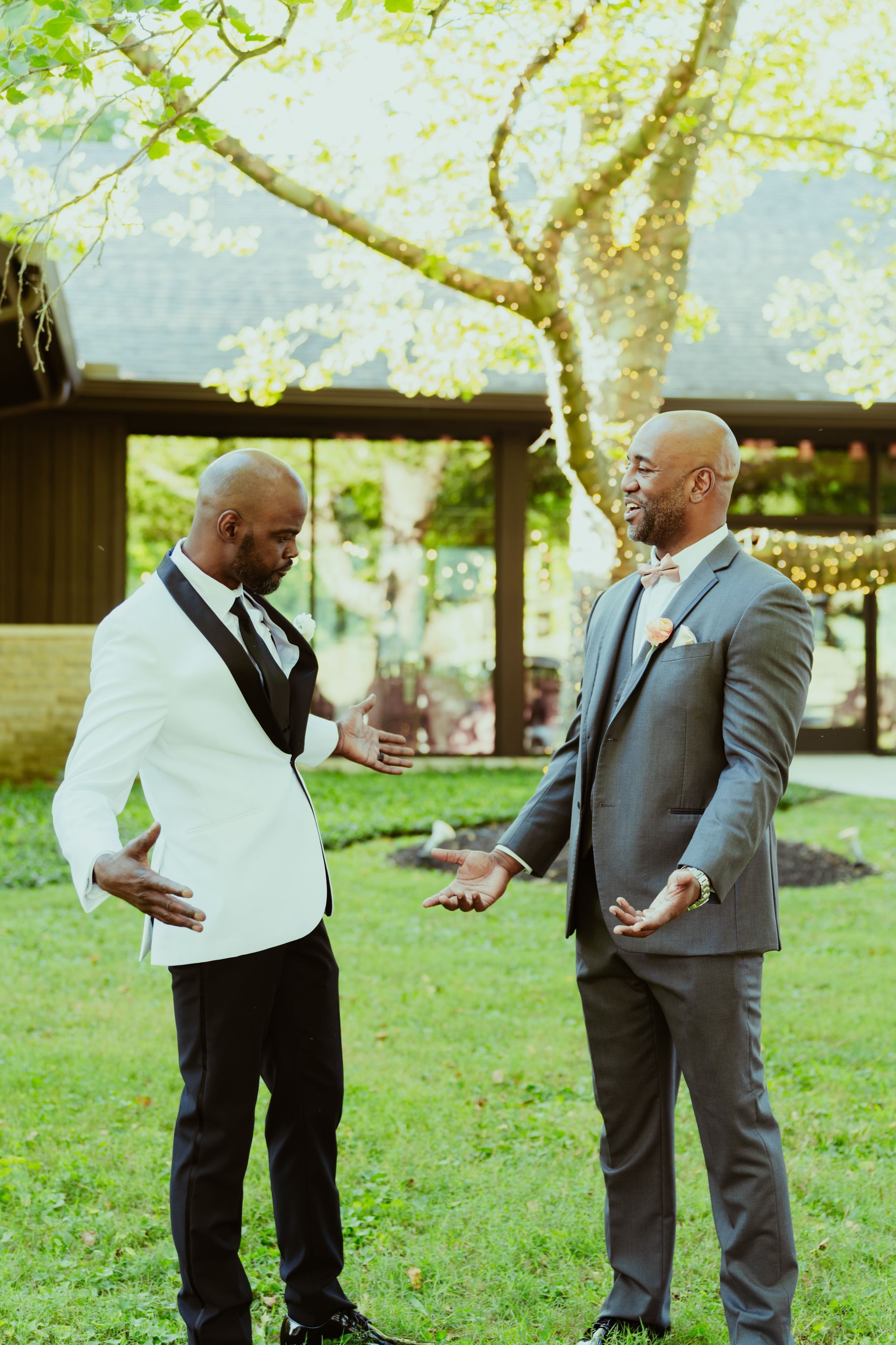 Two men in suits are standing next to each other on a lush green field.