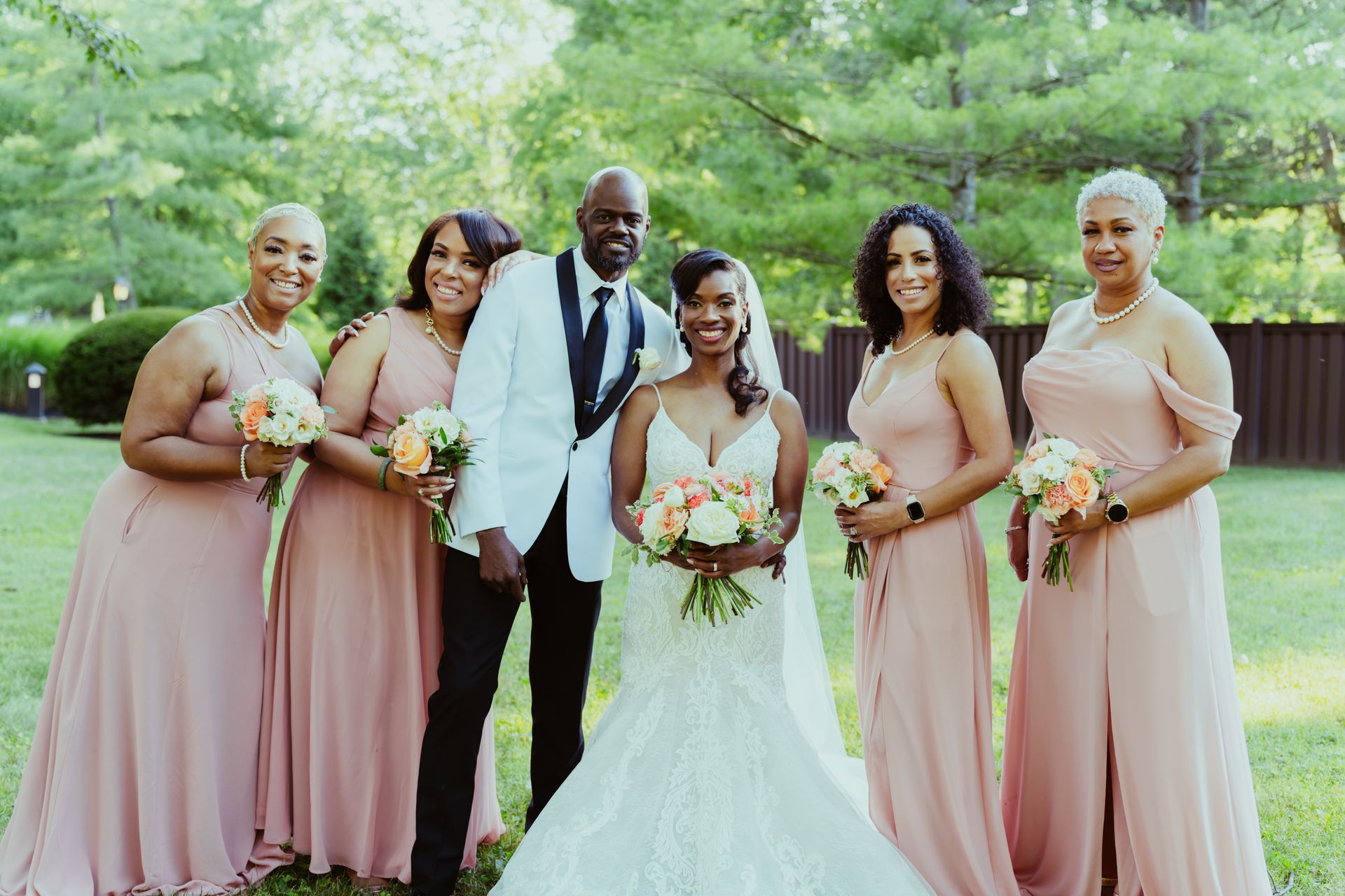The bride and groom are posing for a picture with their bridesmaids.