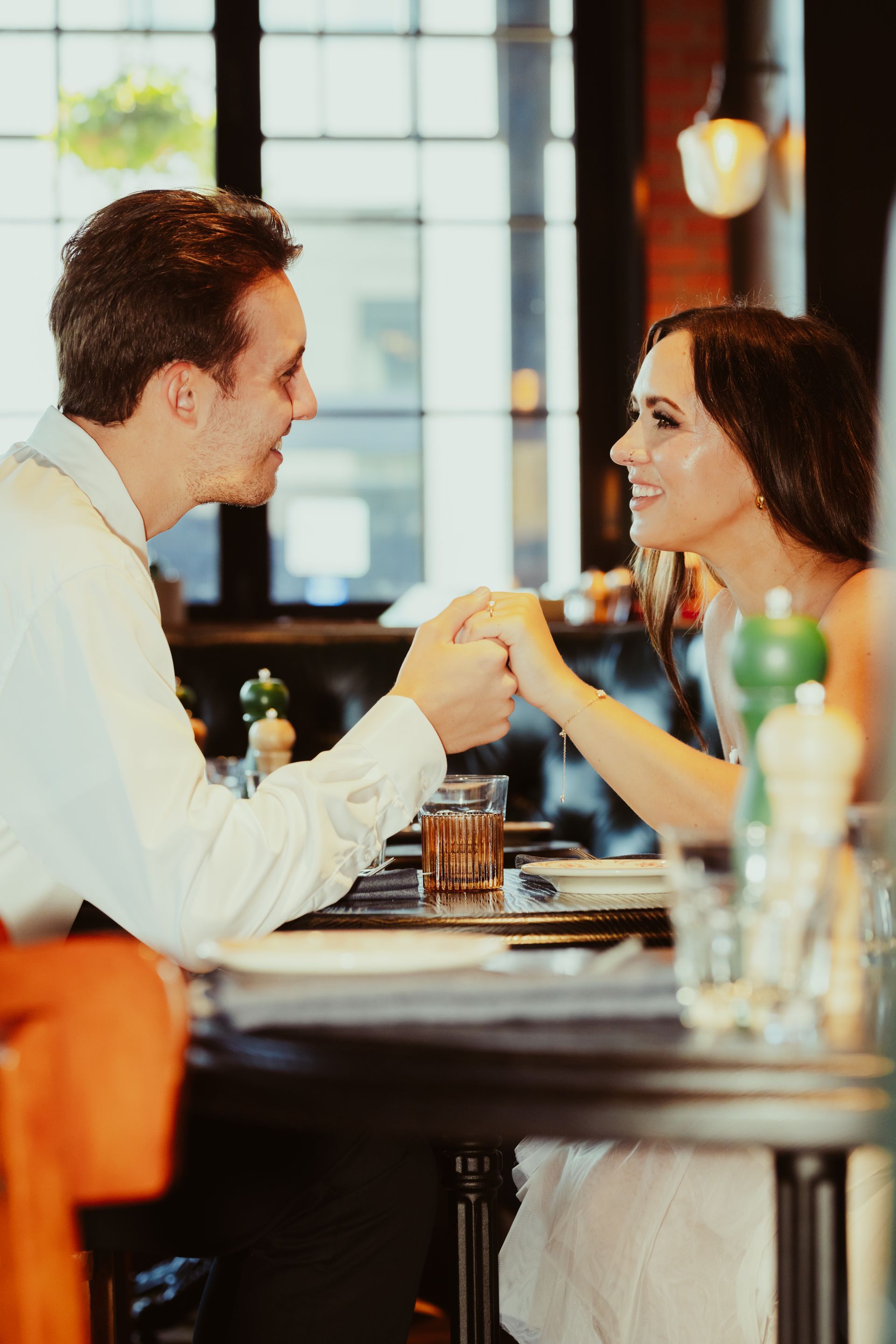 A man and a woman are holding hands while sitting at a table in a restaurant.