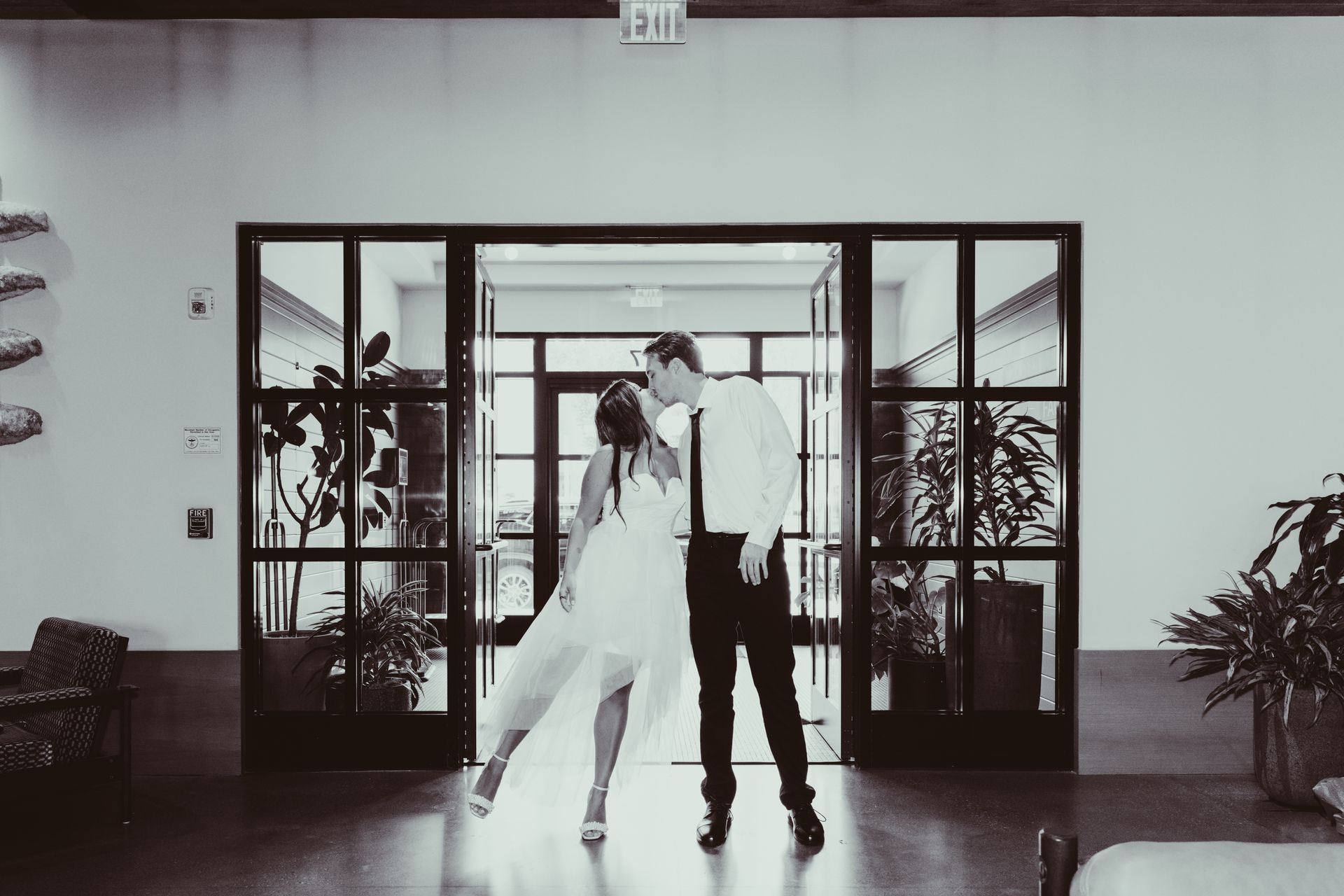 A bride and groom are kissing in a hallway.