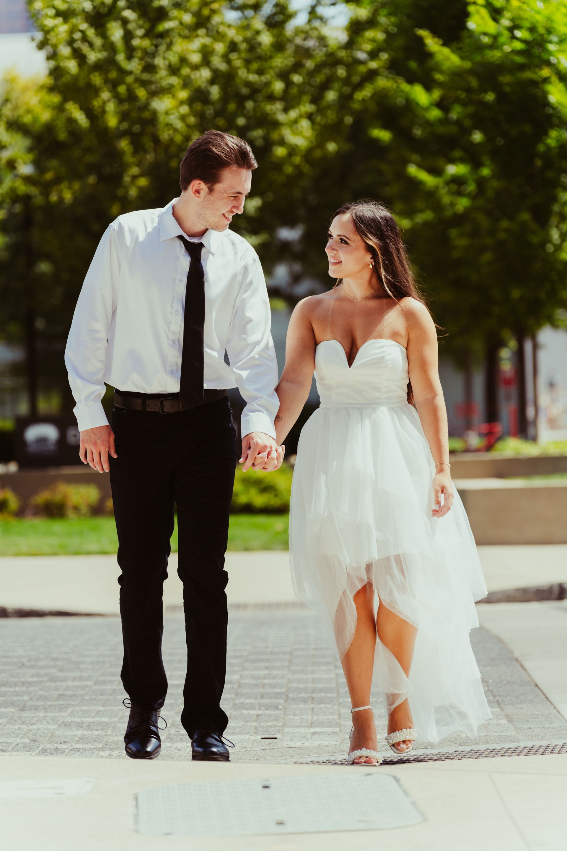 A bride and groom are walking down the street holding hands.