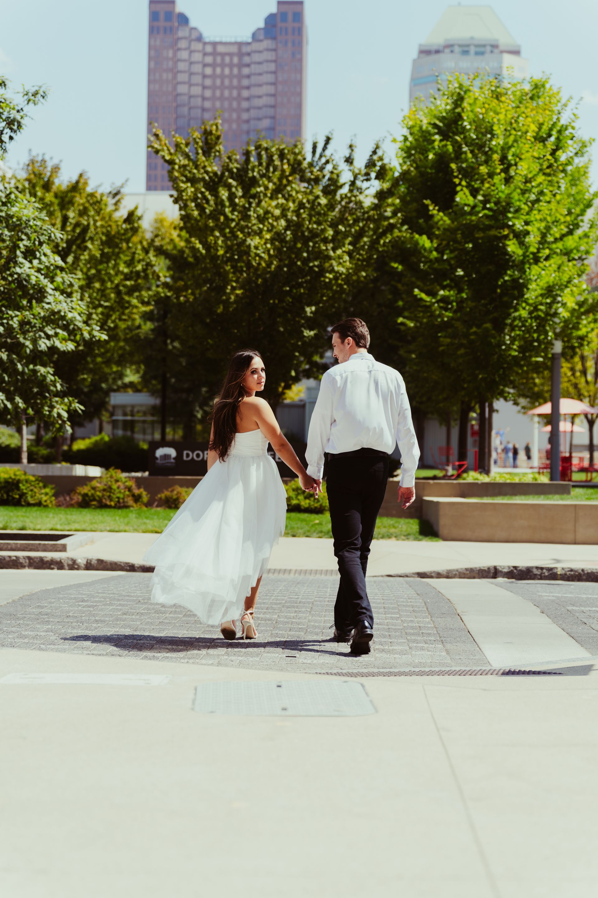 A man and a woman are walking down a sidewalk holding hands.