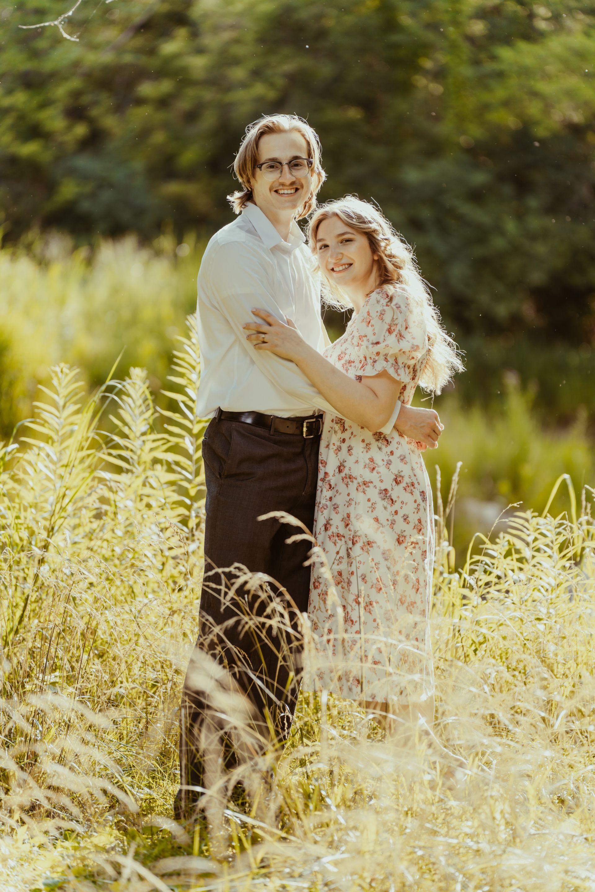 A man and a woman are standing in a field of tall grass.