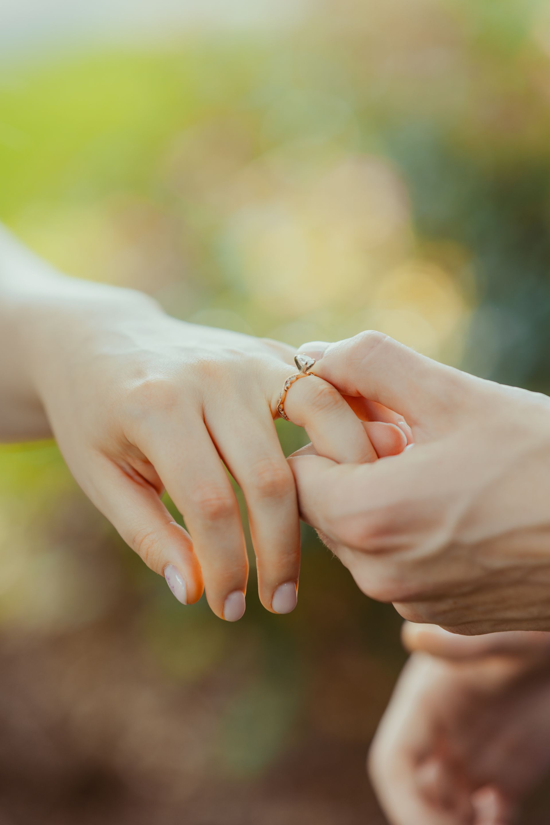 A close up of a person putting a ring on another person 's finger.