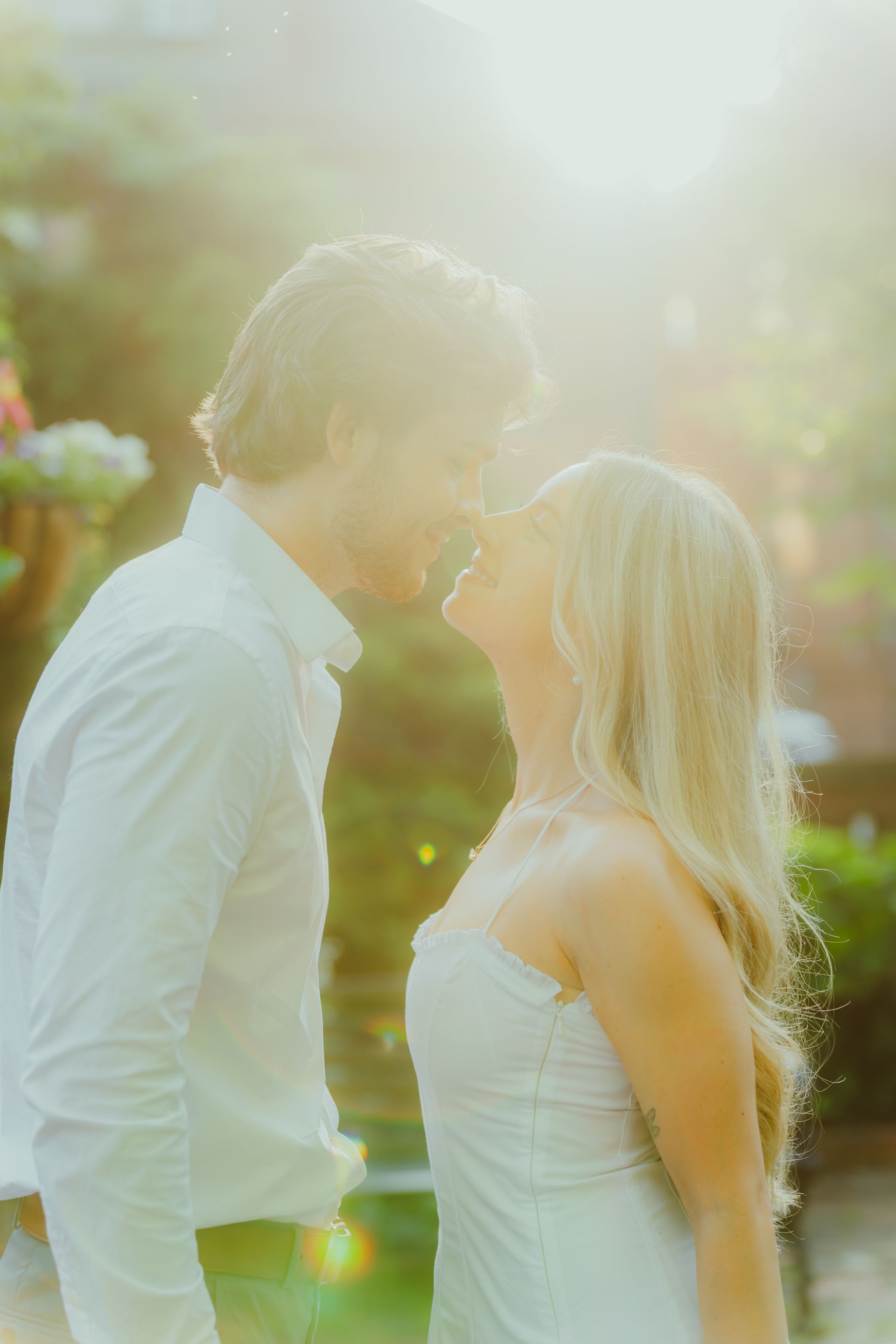A man and a woman are kissing in front of the sun during engagement photo session in downtown columbus..