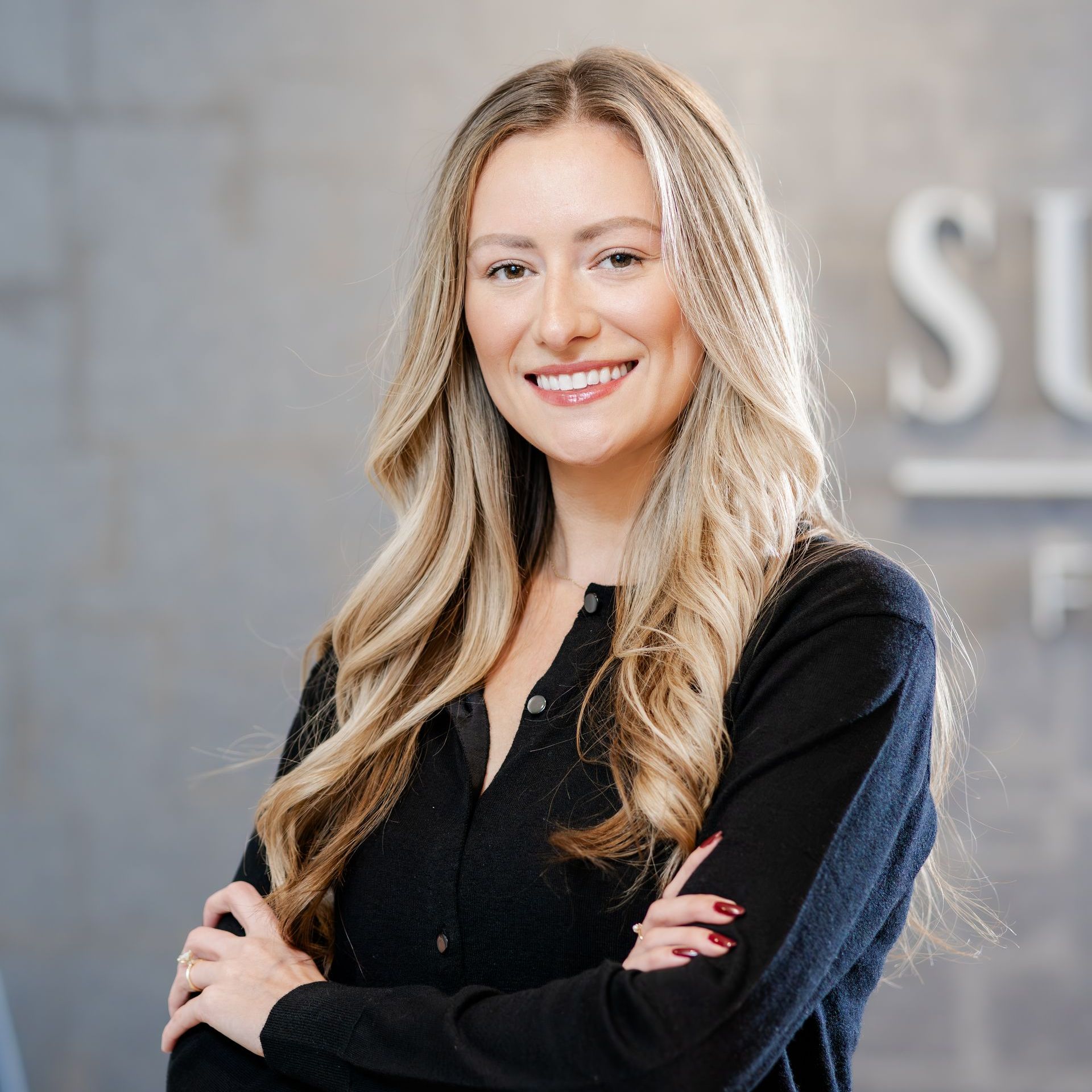 A woman in a black shirt is smiling with her arms crossed.