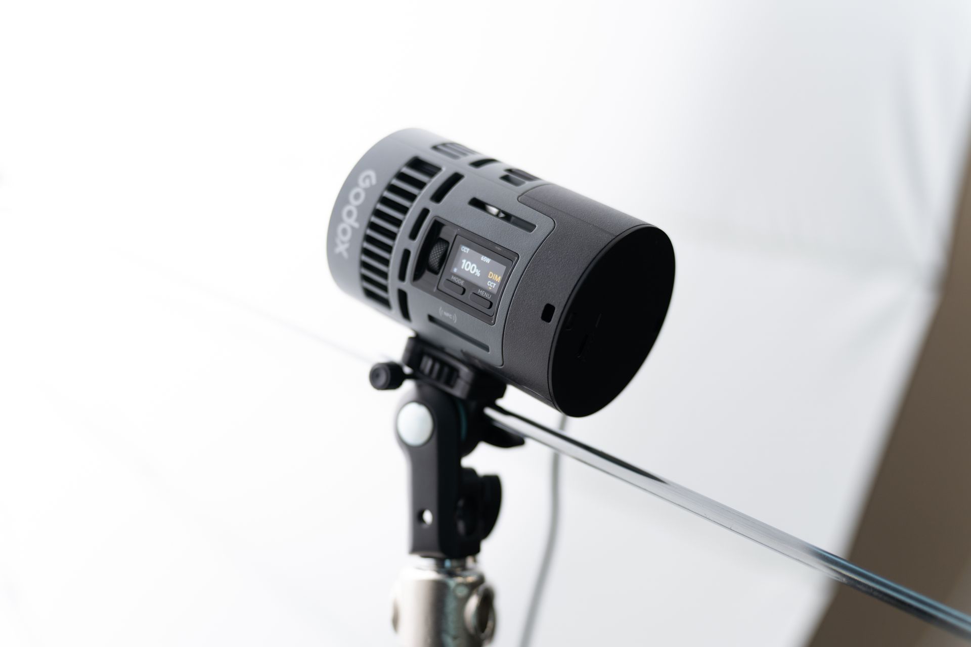 Black Godox light, mounted on a stand, next to a white softbox in a studio.
