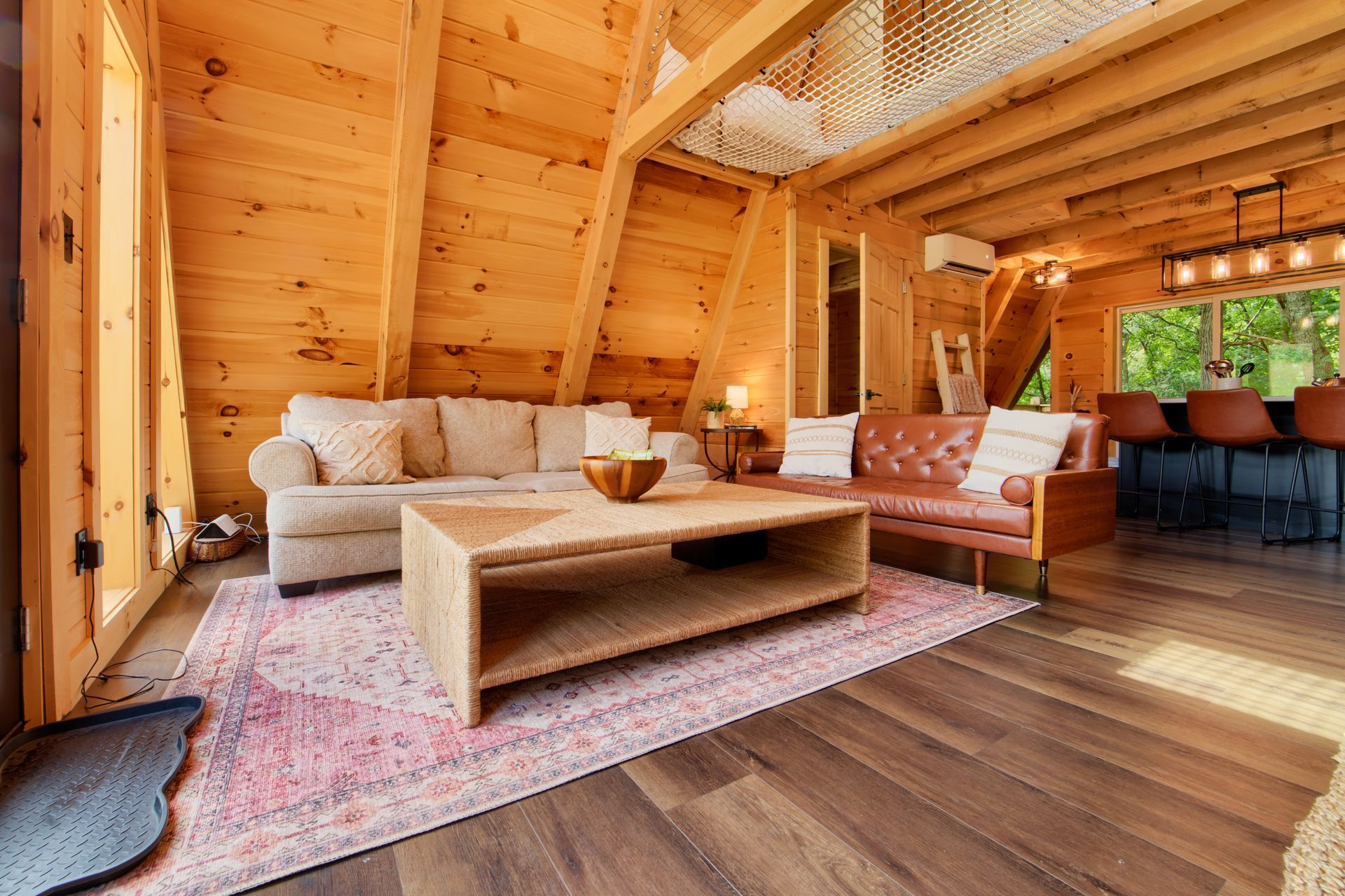 A living room in a log cabin with a couch , coffee table , and rug.