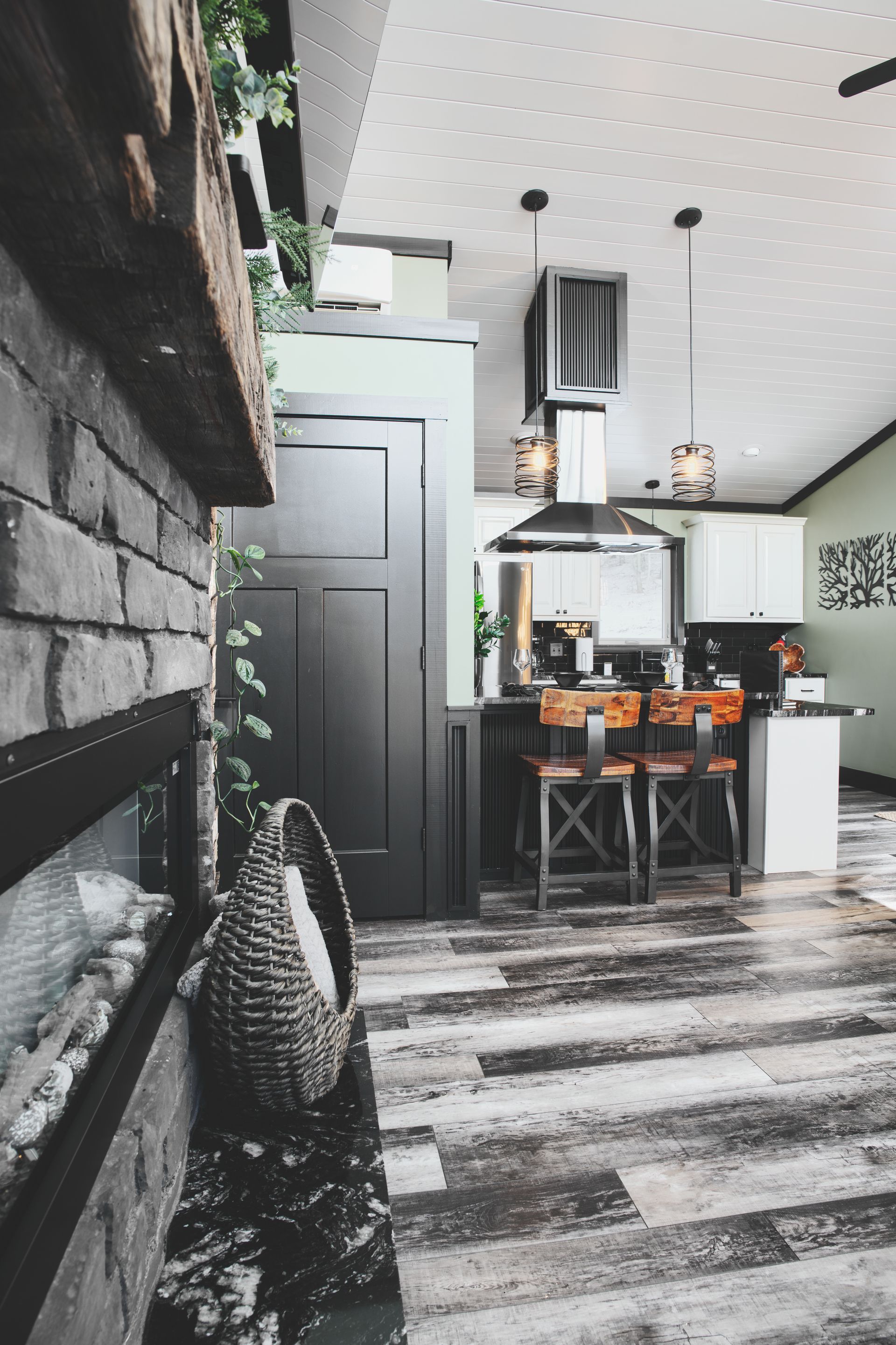 A kitchen with a black door , white cabinets , and wooden floors.