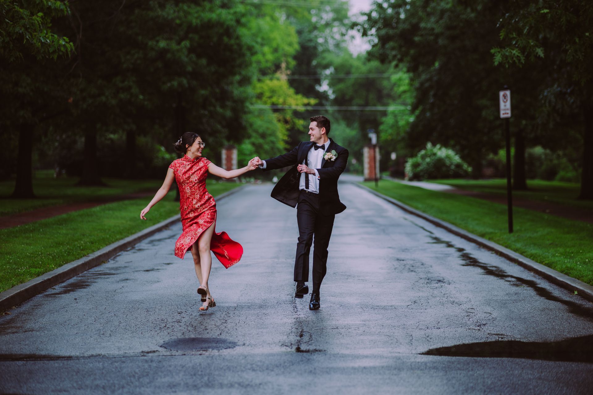 Couple dancing hand in hand on a wet road in the rain, one in a red dress and one in a suit
