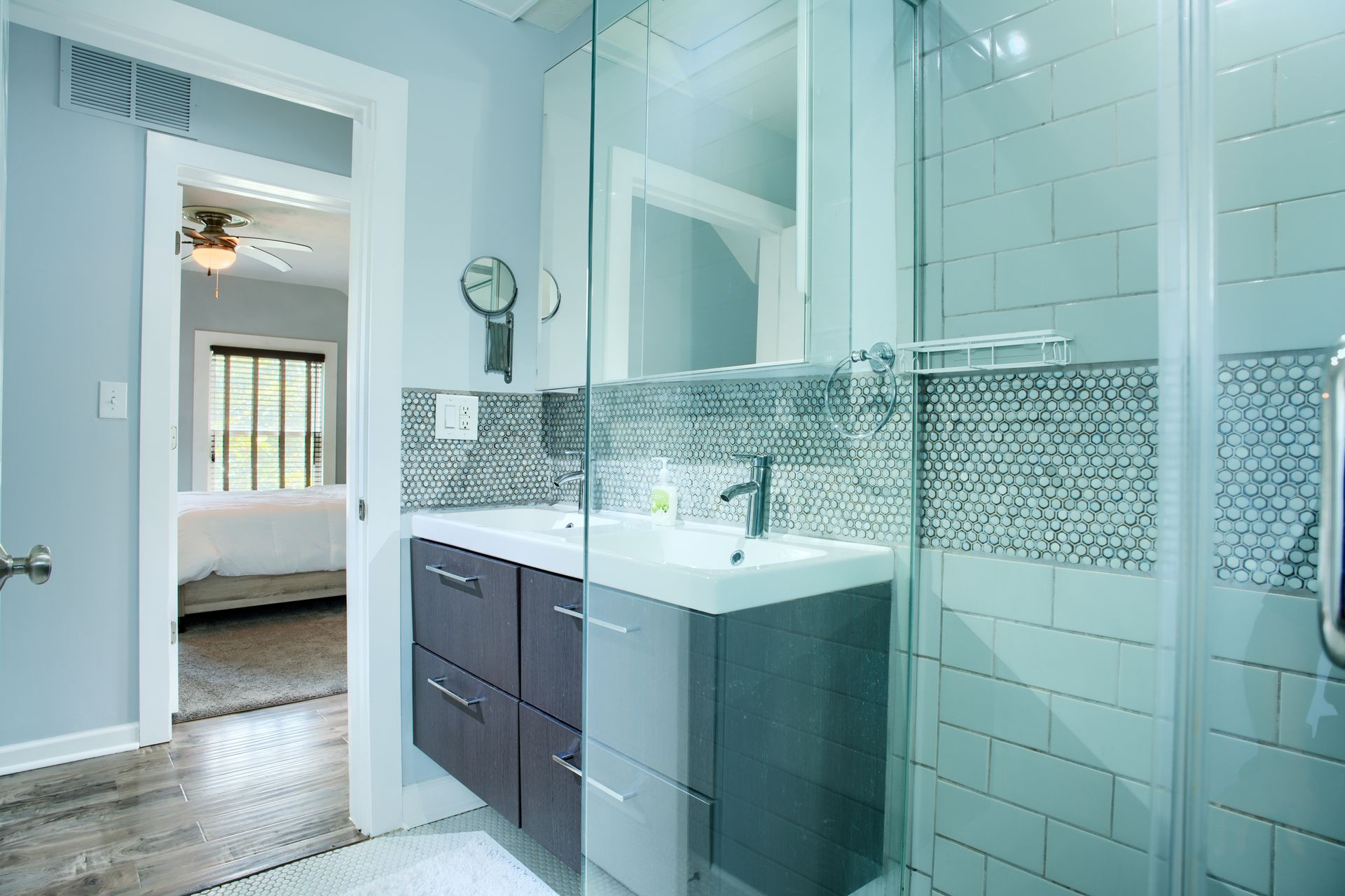 A bathroom with a sink , mirror , and walk in shower.