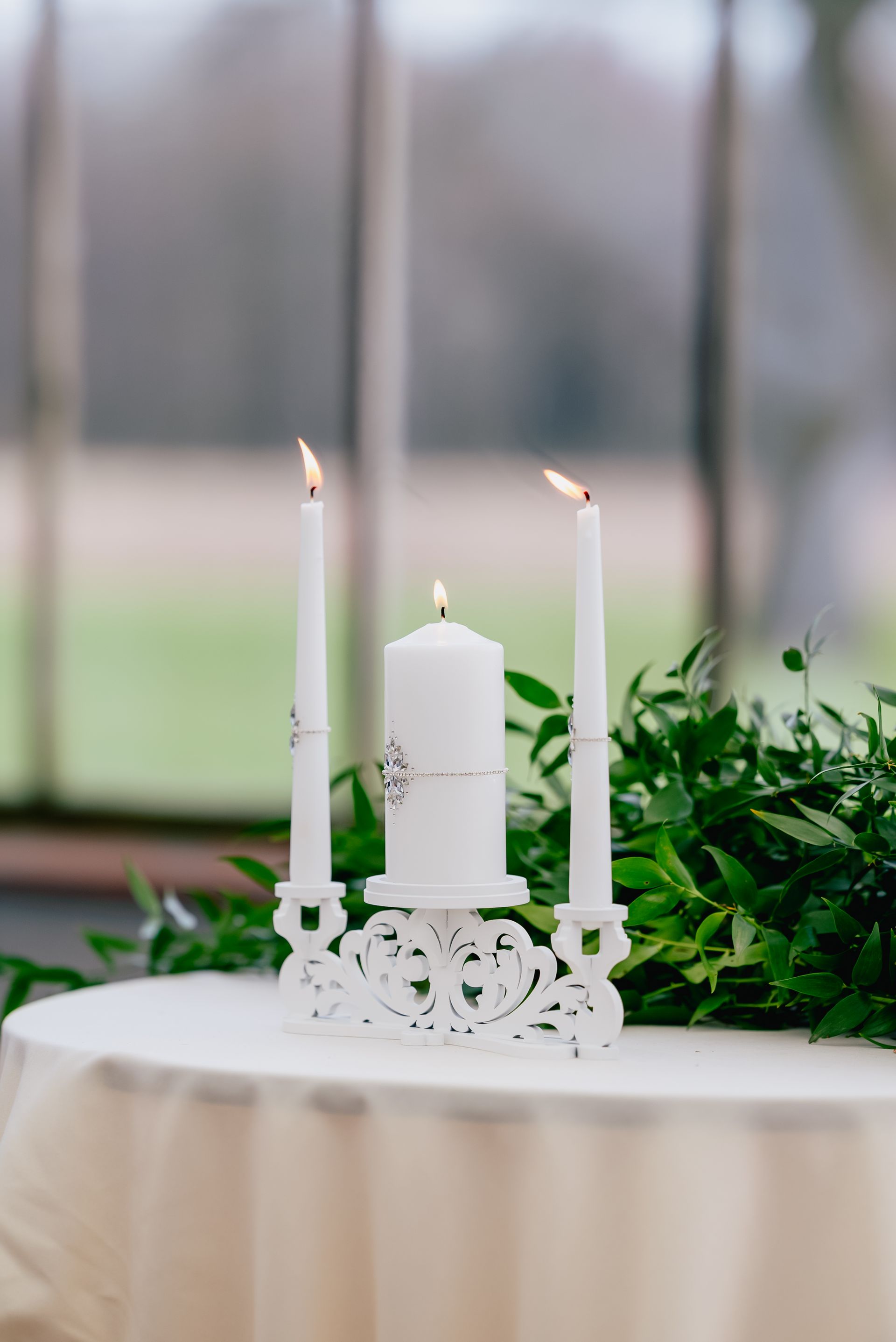 Three white candles are sitting on top of a white table.