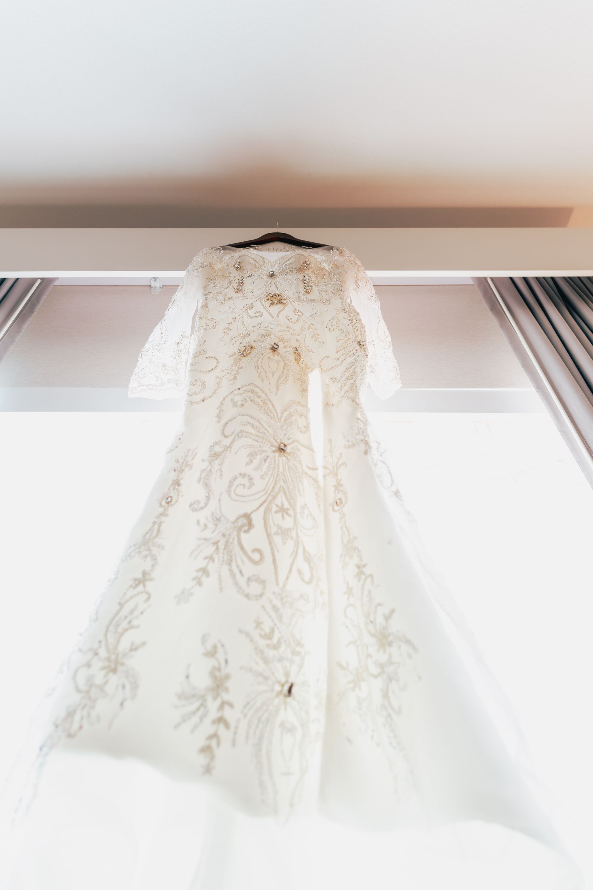 A wedding dress is hanging from the ceiling in a room.