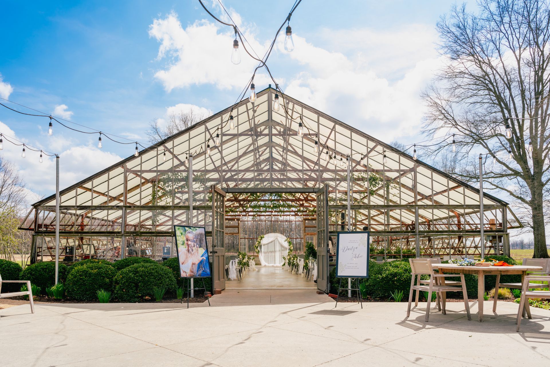 A large greenhouse with a table and chairs in front of it.