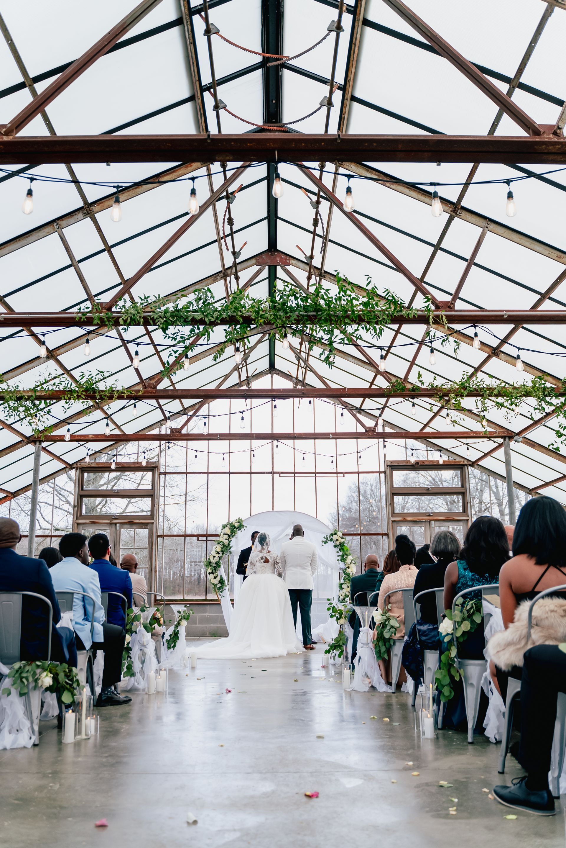 A bride and groom are getting married in a jorgensen farms greenhouse.