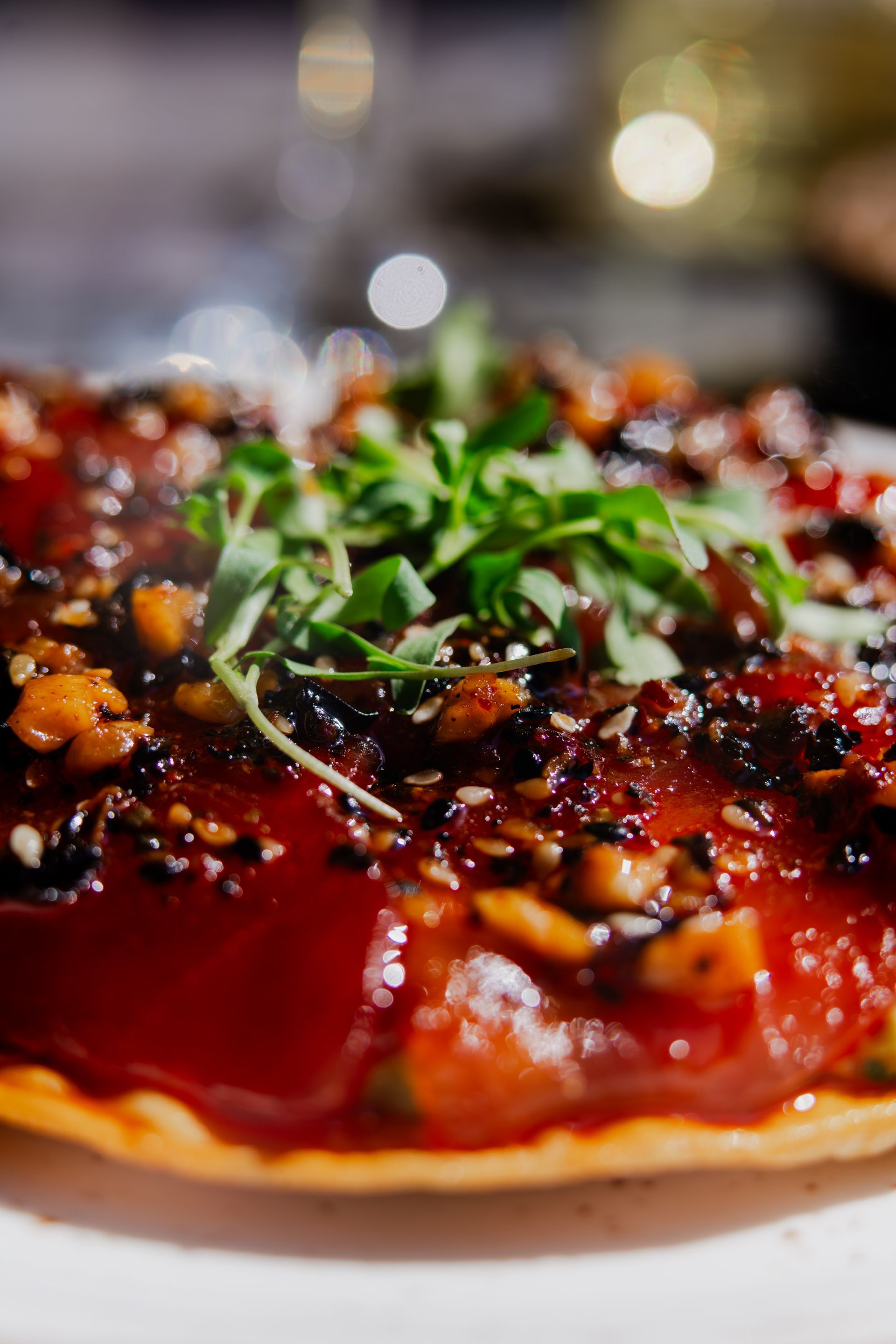 A close up of a pizza with tomatoes and parsley on a table.