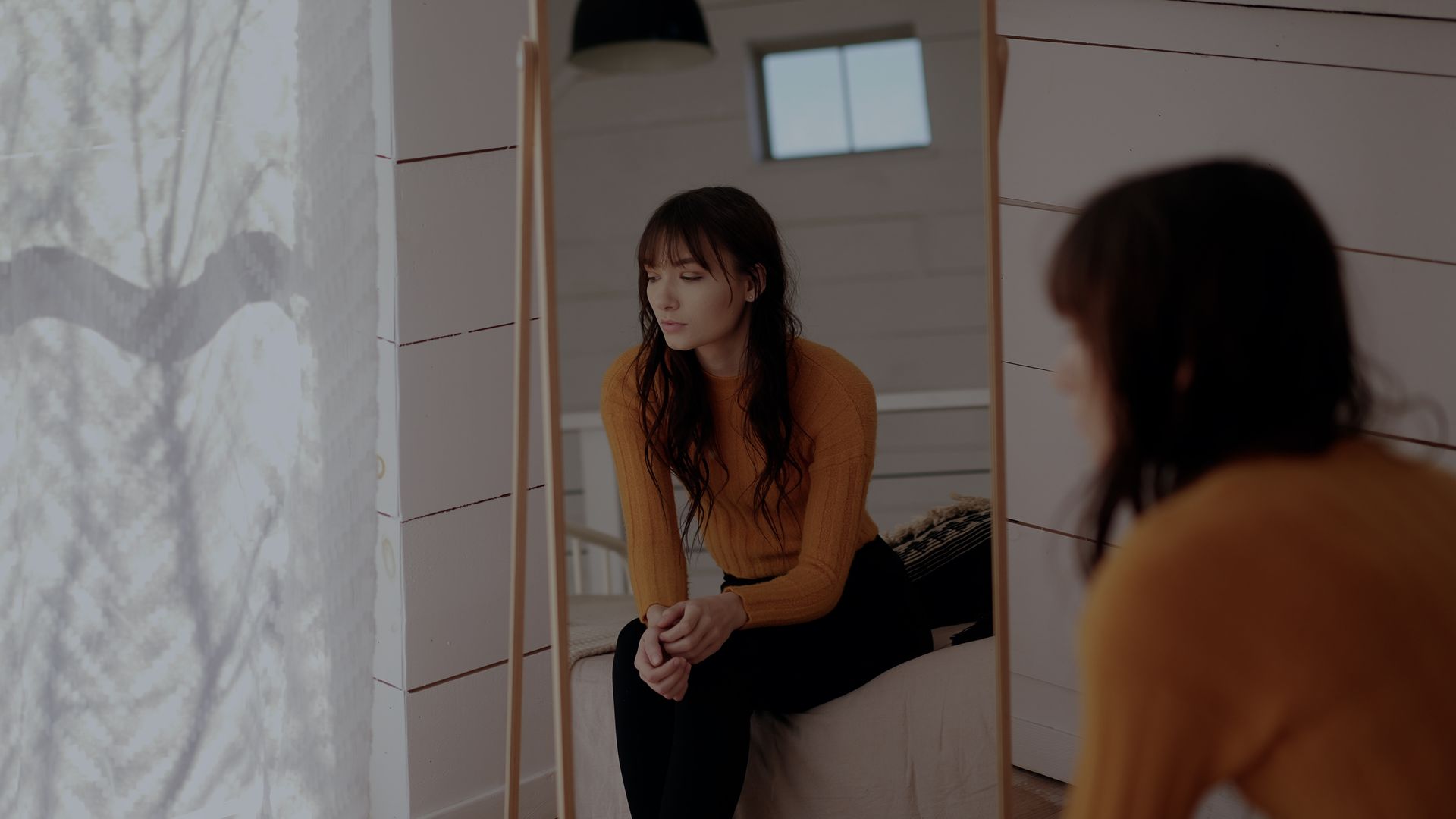 a woman is sitting in front of a mirror looking at herself .