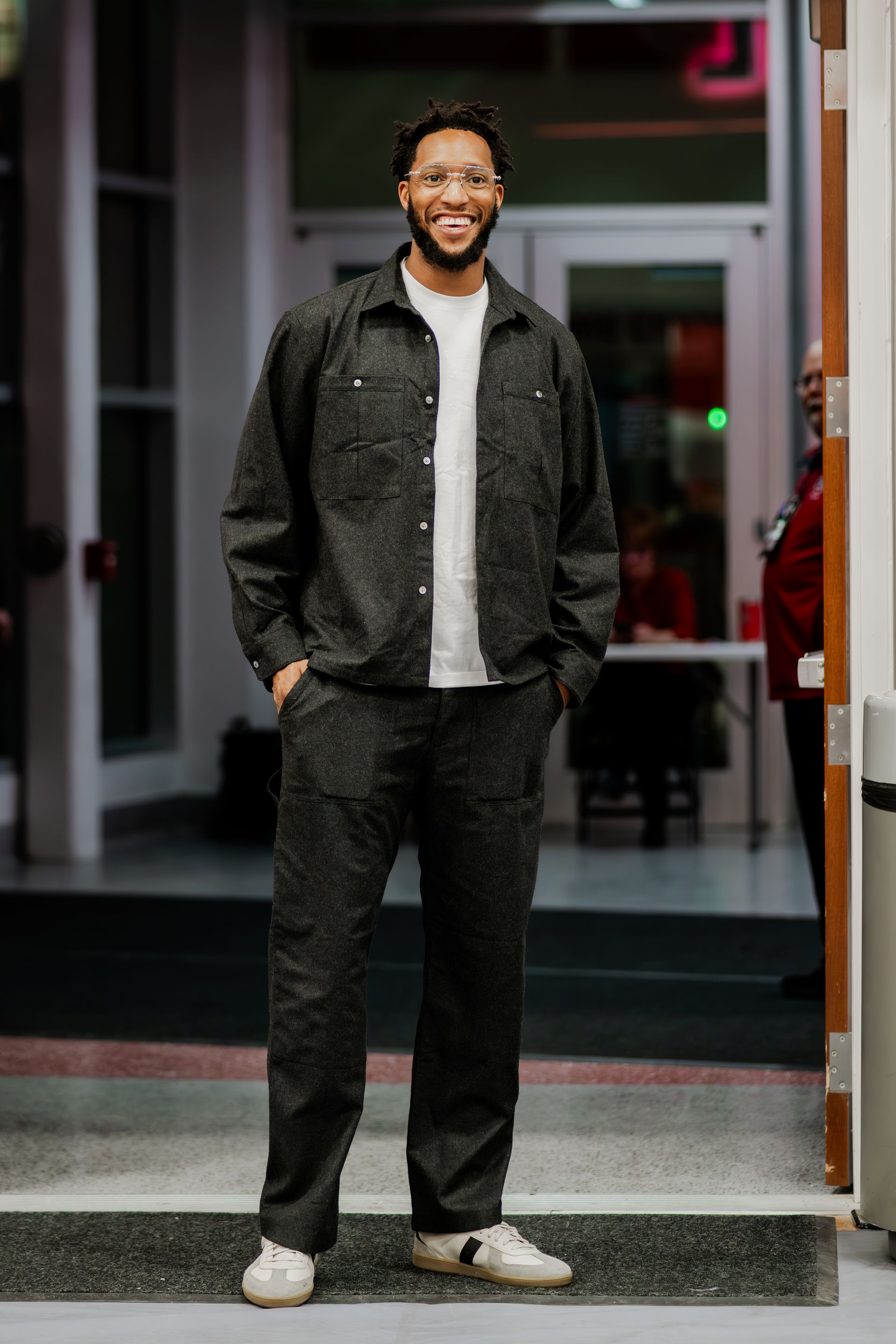 Person in black jacket and pants, white shirt. Standing inside building, smiling.Midwest Cards | Event Photography
