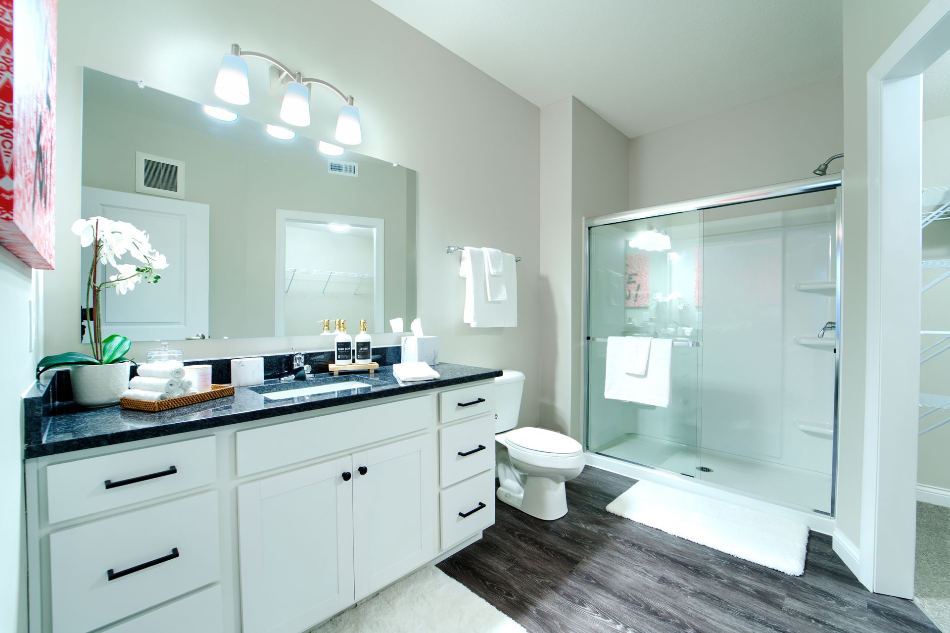 A bathroom with a toilet , sink , mirror and shower.