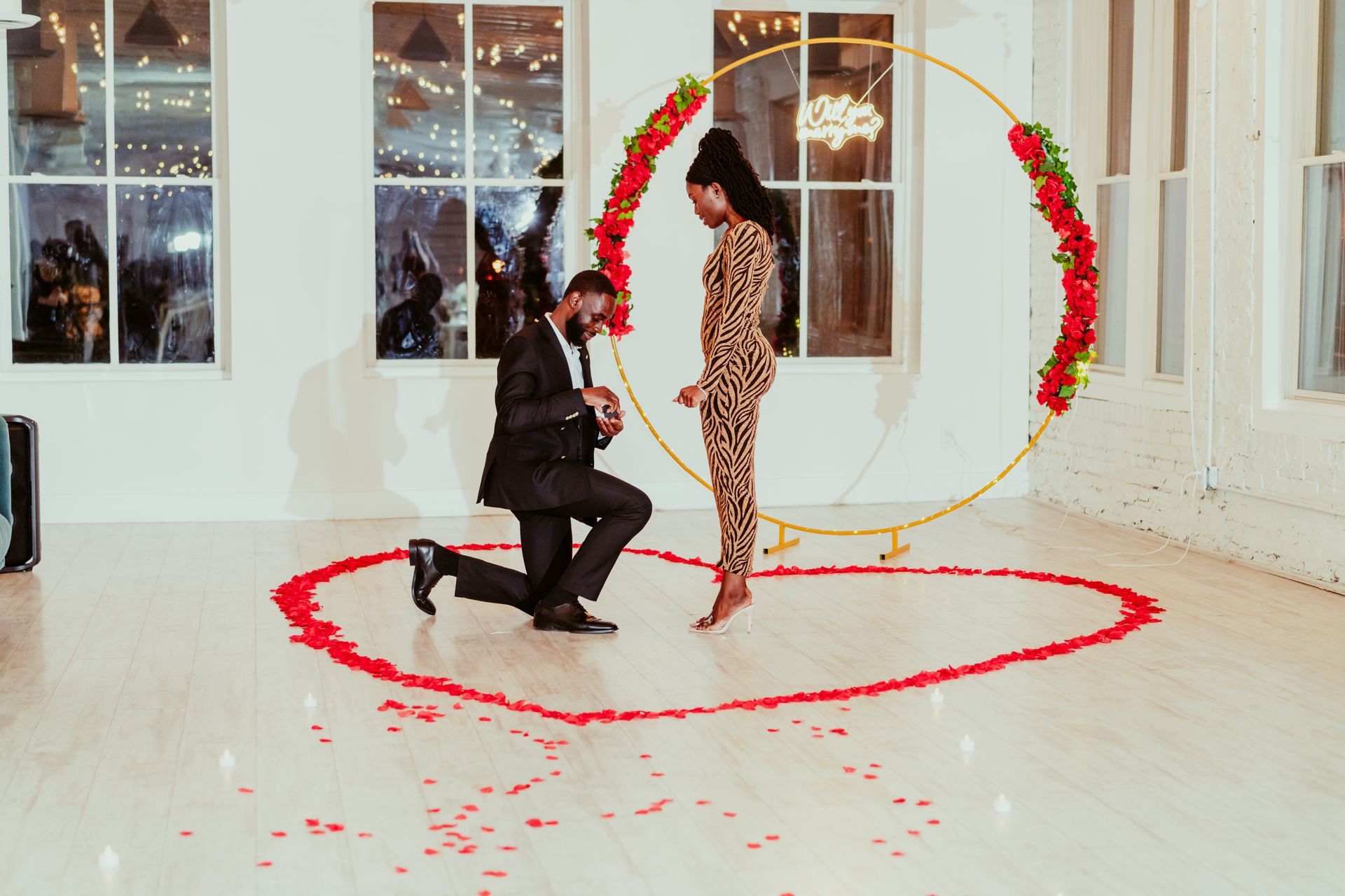 A man is kneeling down in front of a woman in a room.