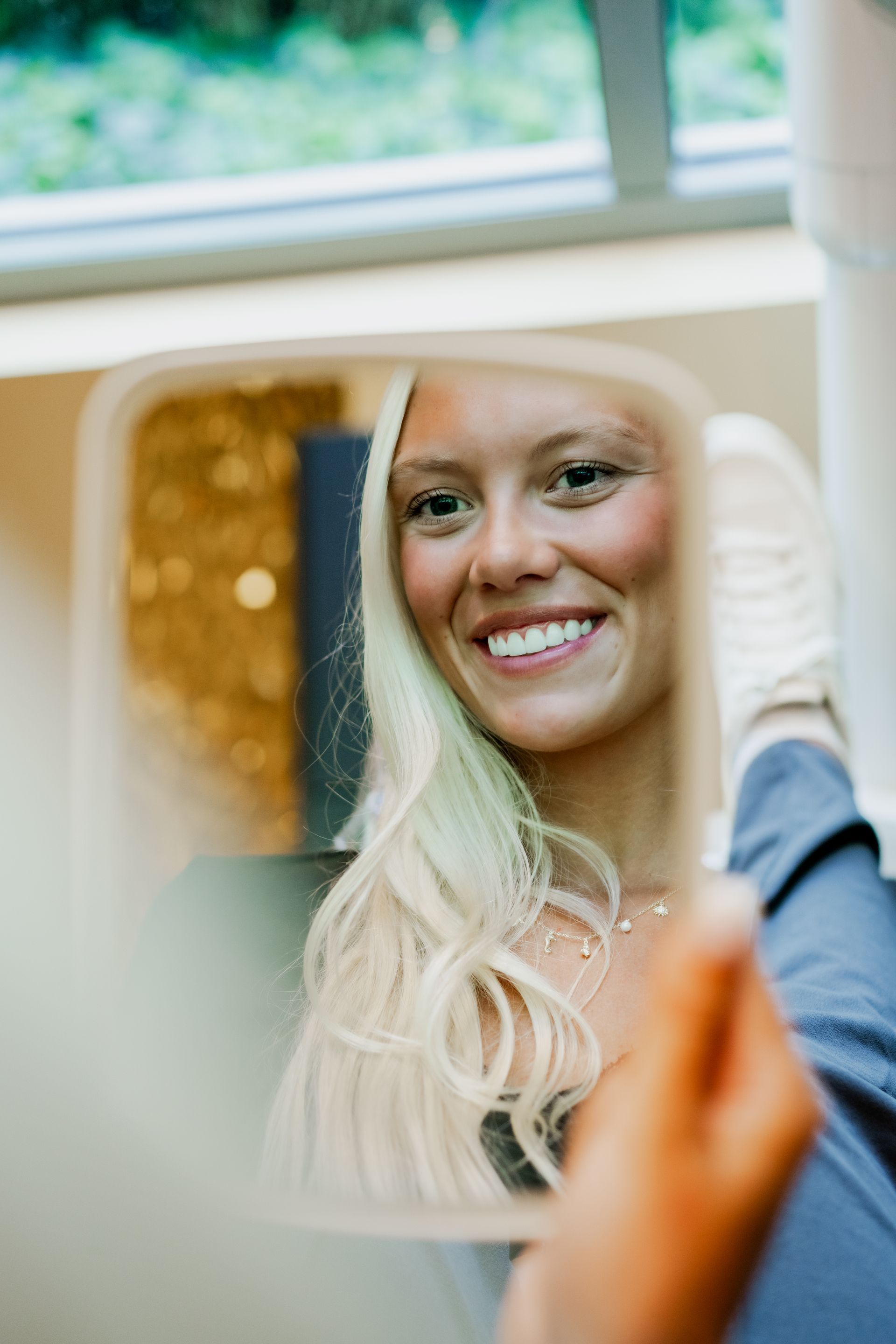 A woman is smiling while looking at herself in a mirror.