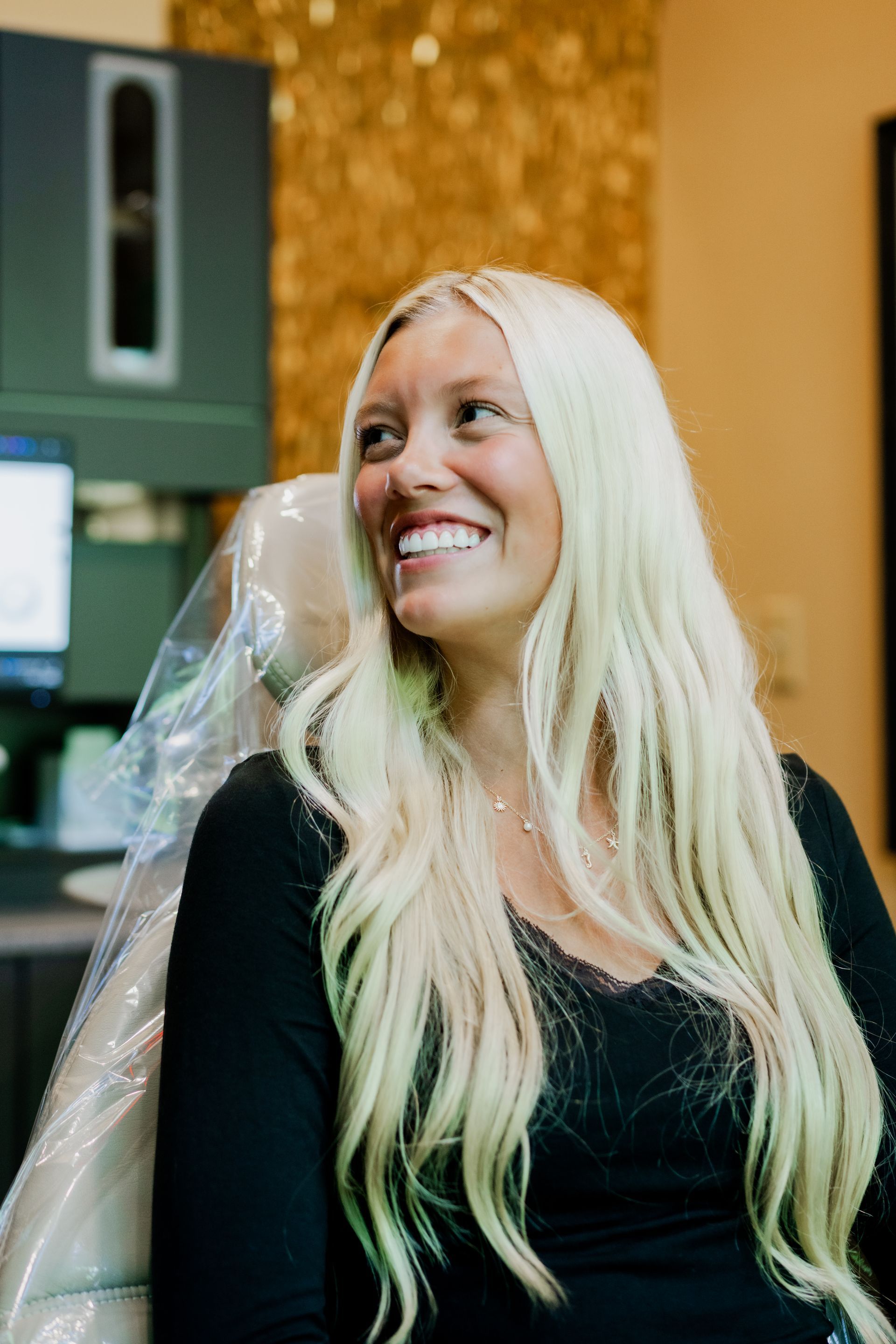 A woman is sitting in a dental chair and smiling.