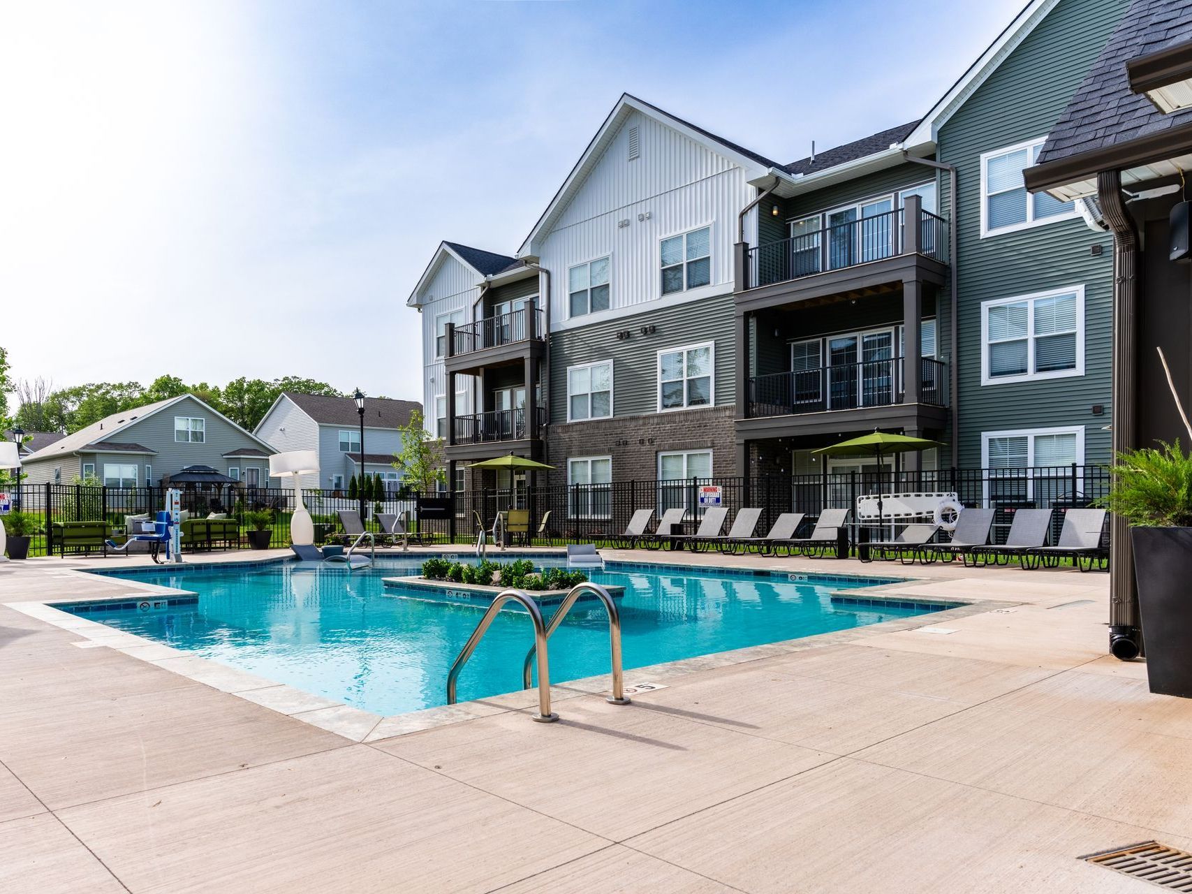 A large swimming pool in front of a large apartment building.